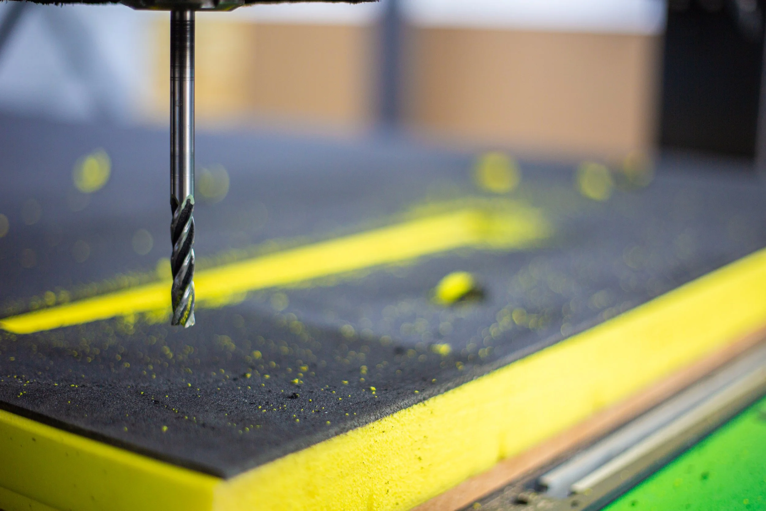 CNC machine cutting a tool-shaped section into yellow and black protective foam at AIC.
