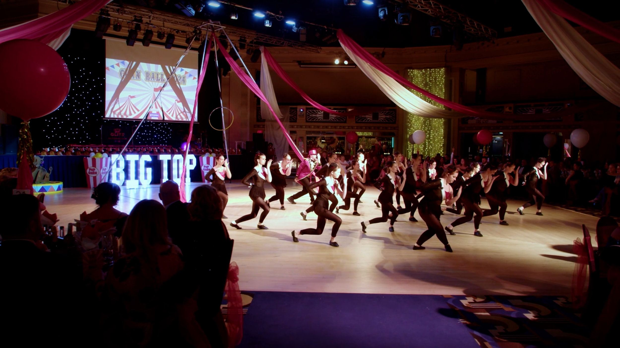 Large group of dancers performing on stage in front of guests at the CLAN Cancer Support annual ball.