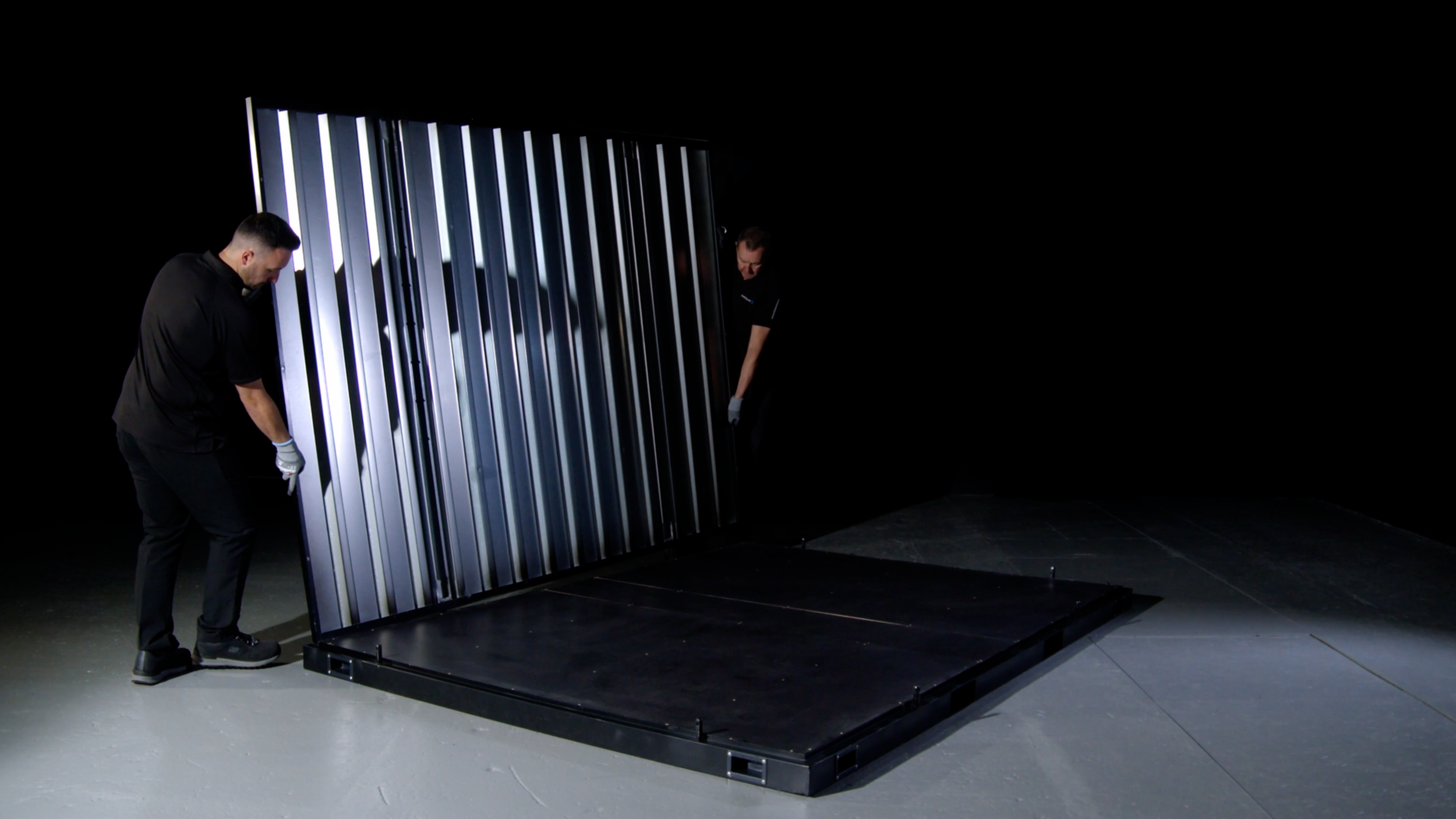 Two workers assembling the Site Store modular container inside a dark warehouse.