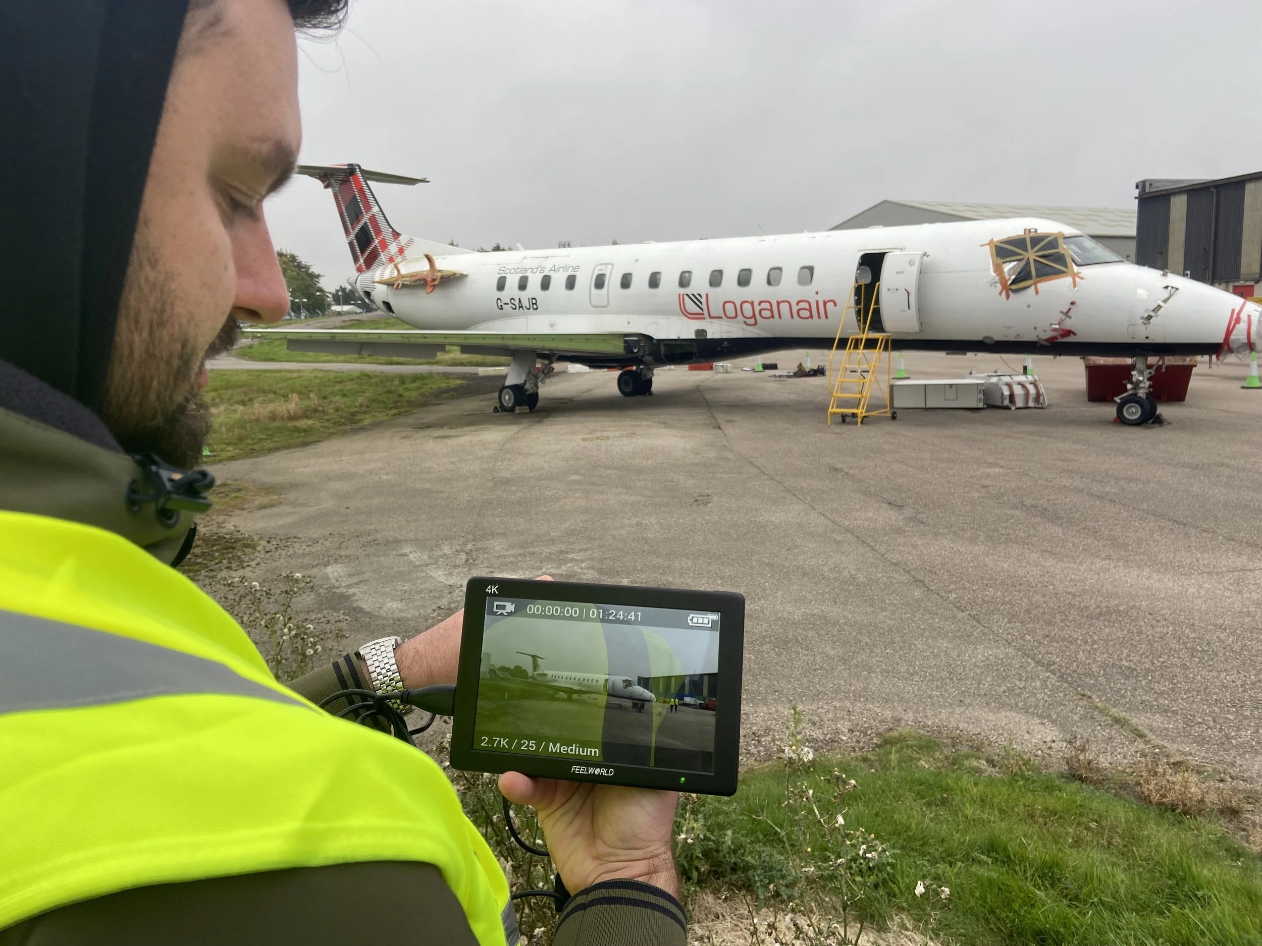 Farsight crew member holding a camera monitor displaying the aircraft, with the aircraft visible behind.