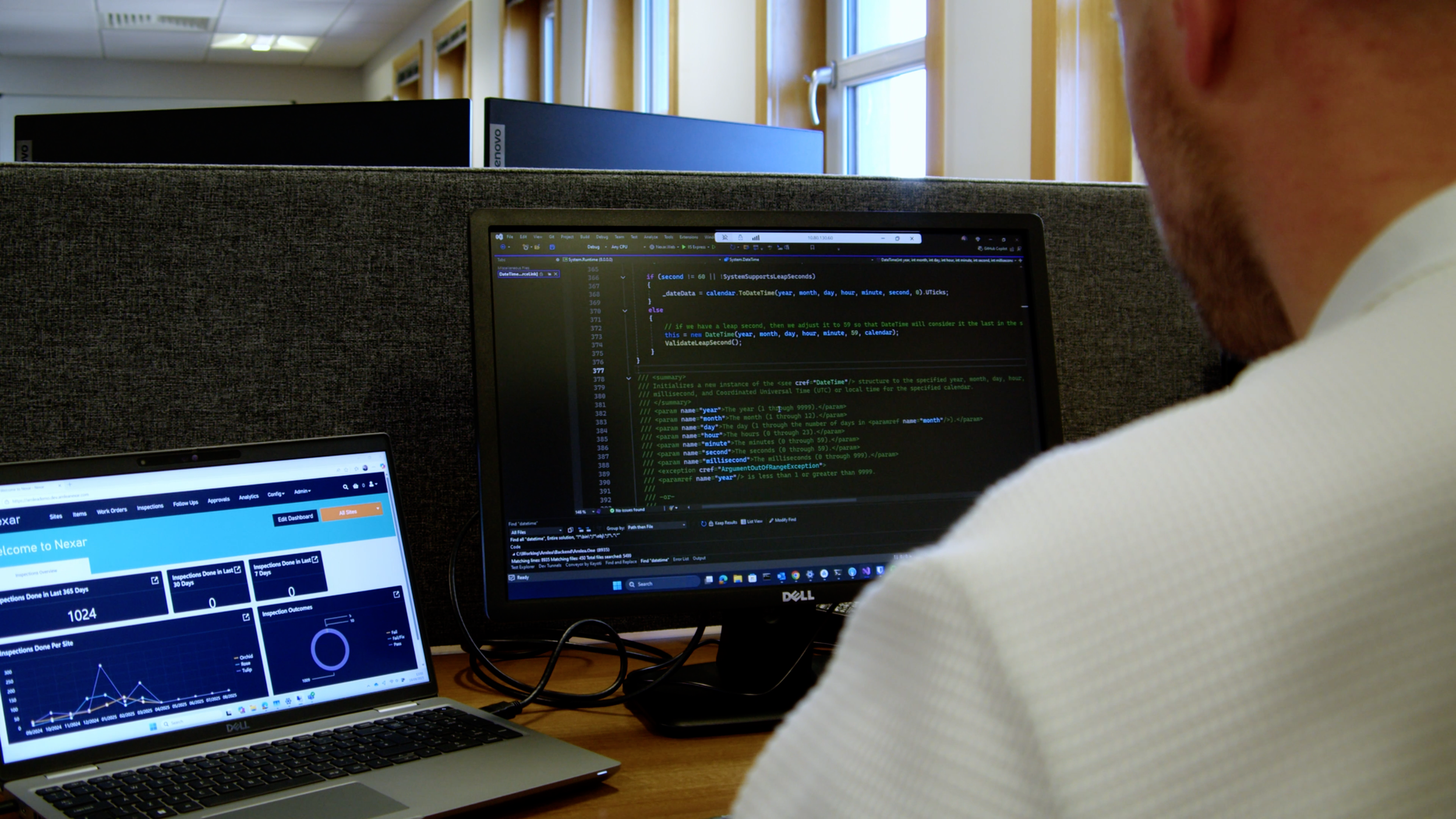 Arnlea Systems team member using NEXAR on a laptop beside a monitor displaying software code.