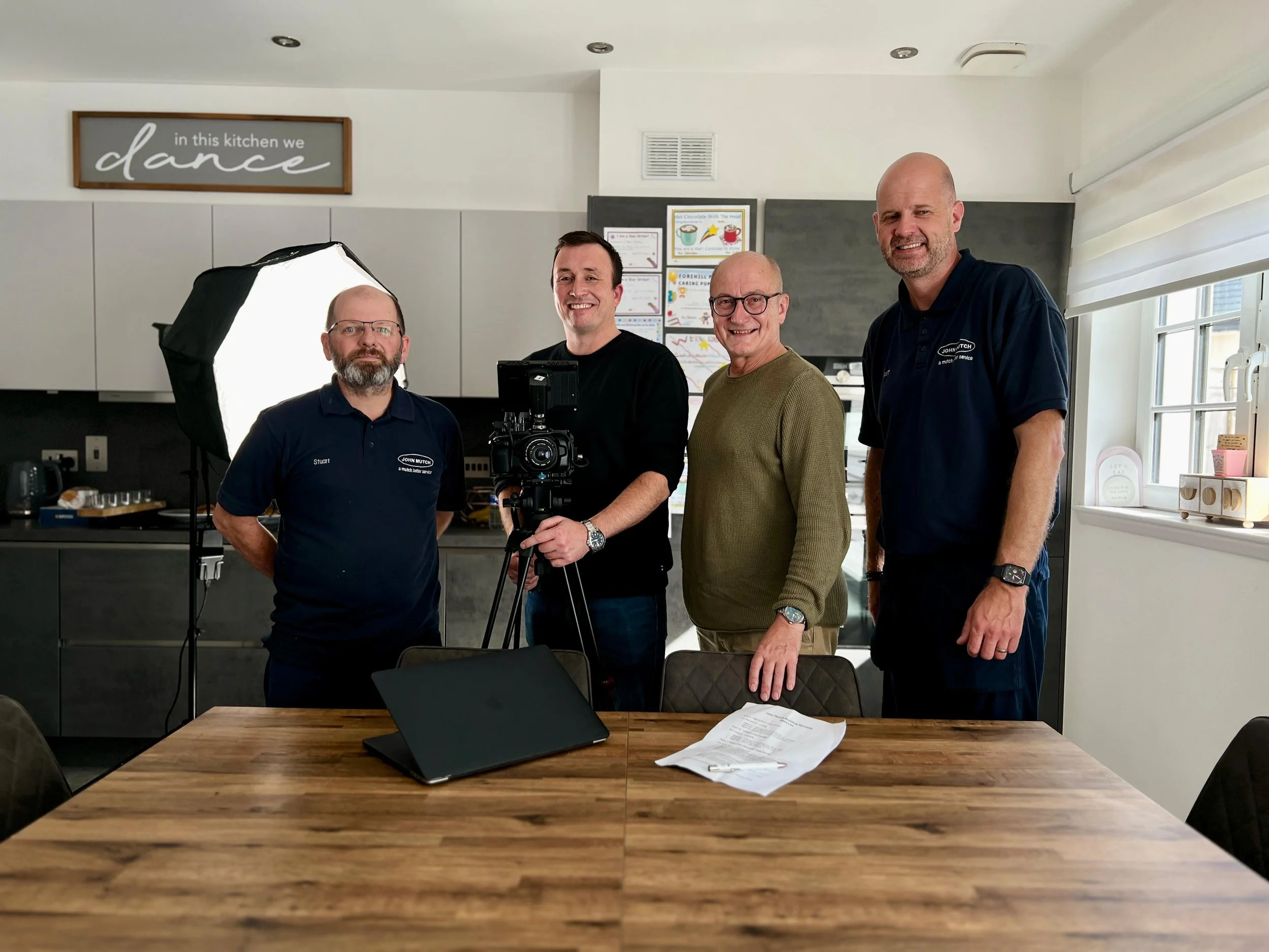Michael Silva holding a camera beside the actor and two directors of John Mutch Building Services.