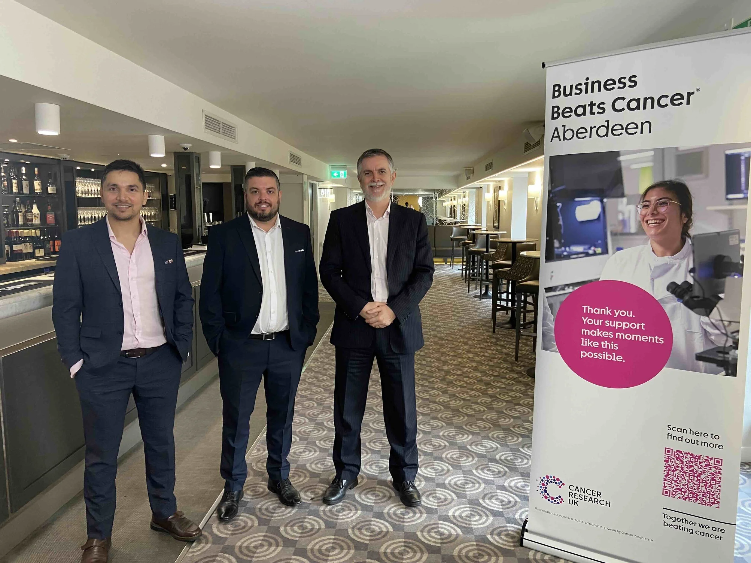 Business Beats Cancer Aberdeen board members posing beside the event’s roll-up banner.