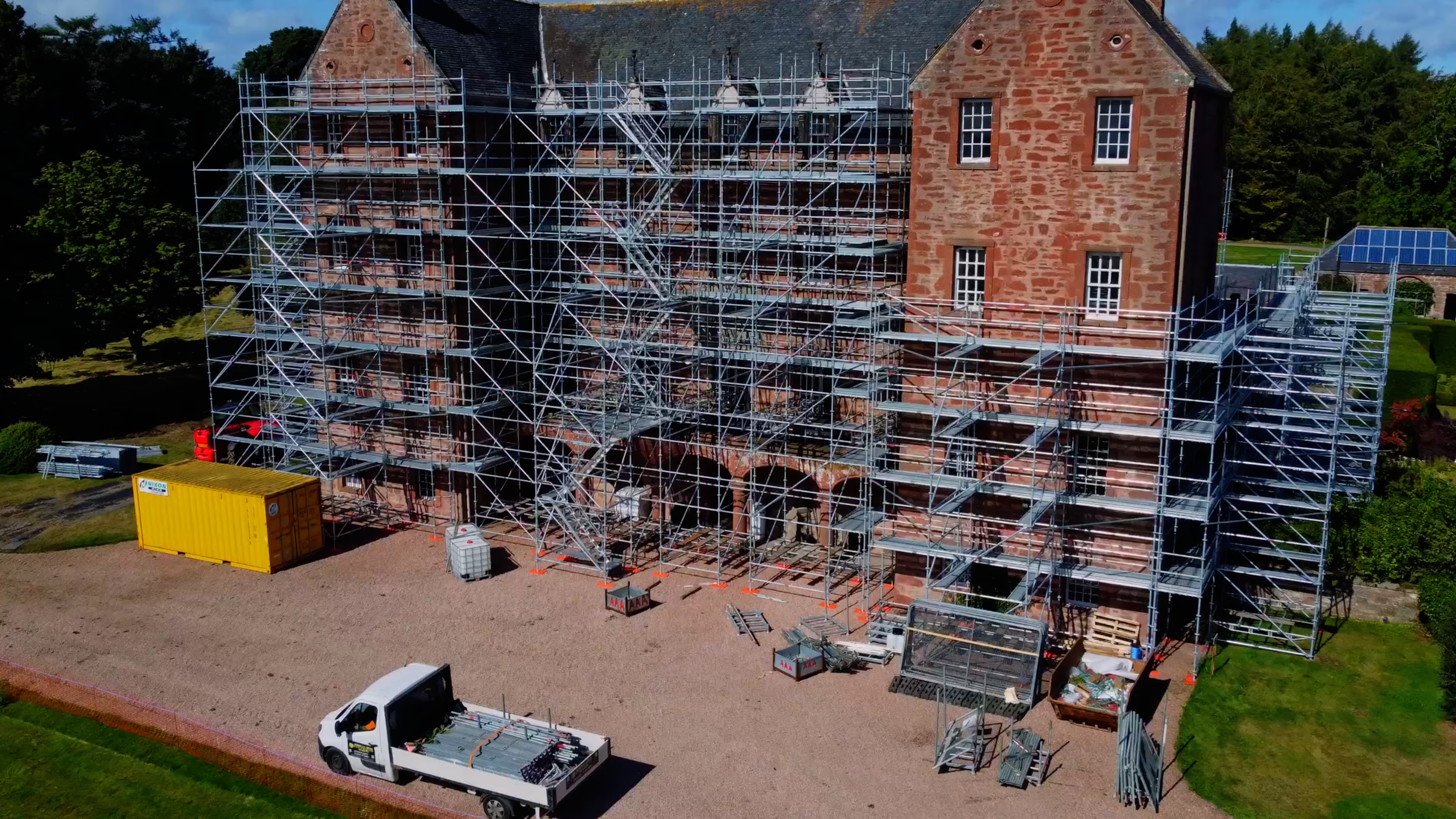 Large property surrounded by scaffolding with an AAA Scaffolding van parked in front.