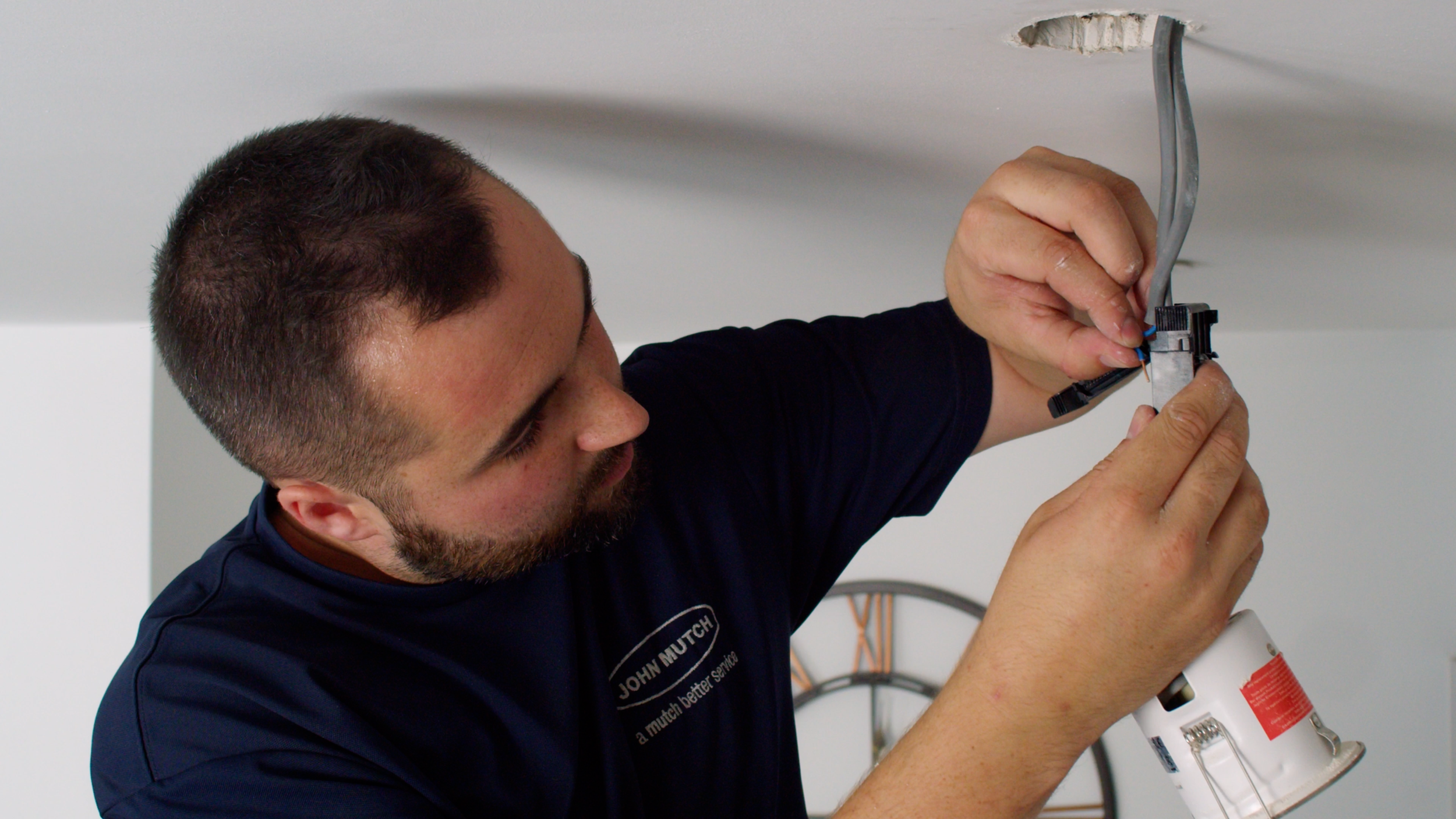 John Mutch Building Services electrician carrying out electrical work on a light.