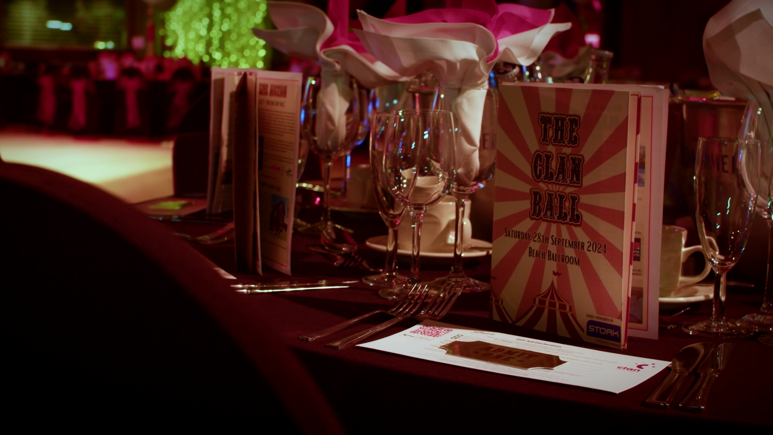 Decorated table setting with the CLAN Cancer Support annual ball programme visible.
