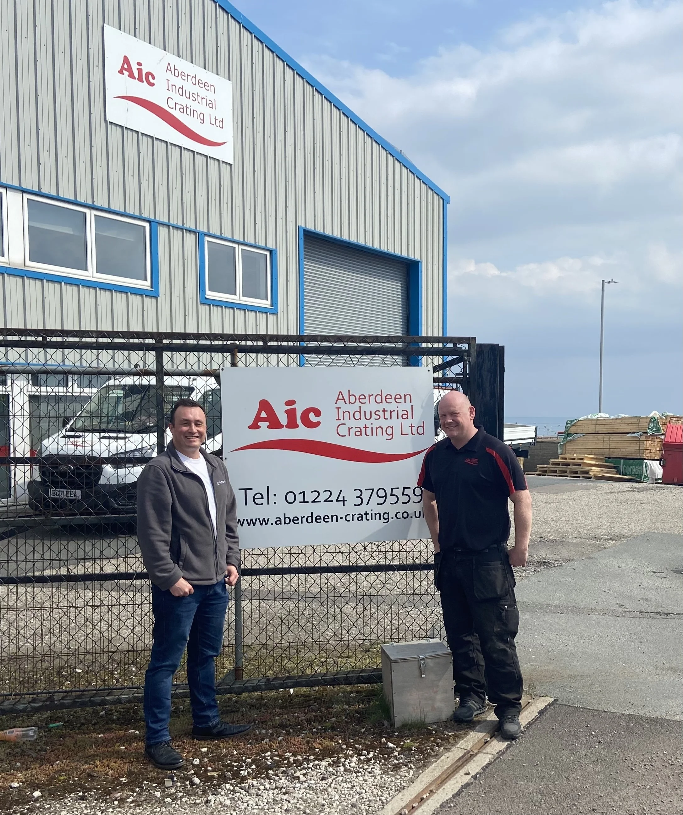 Michael Silva of Farsight and Mike Russell of AIC standing outside the AIC building beside the company sign.