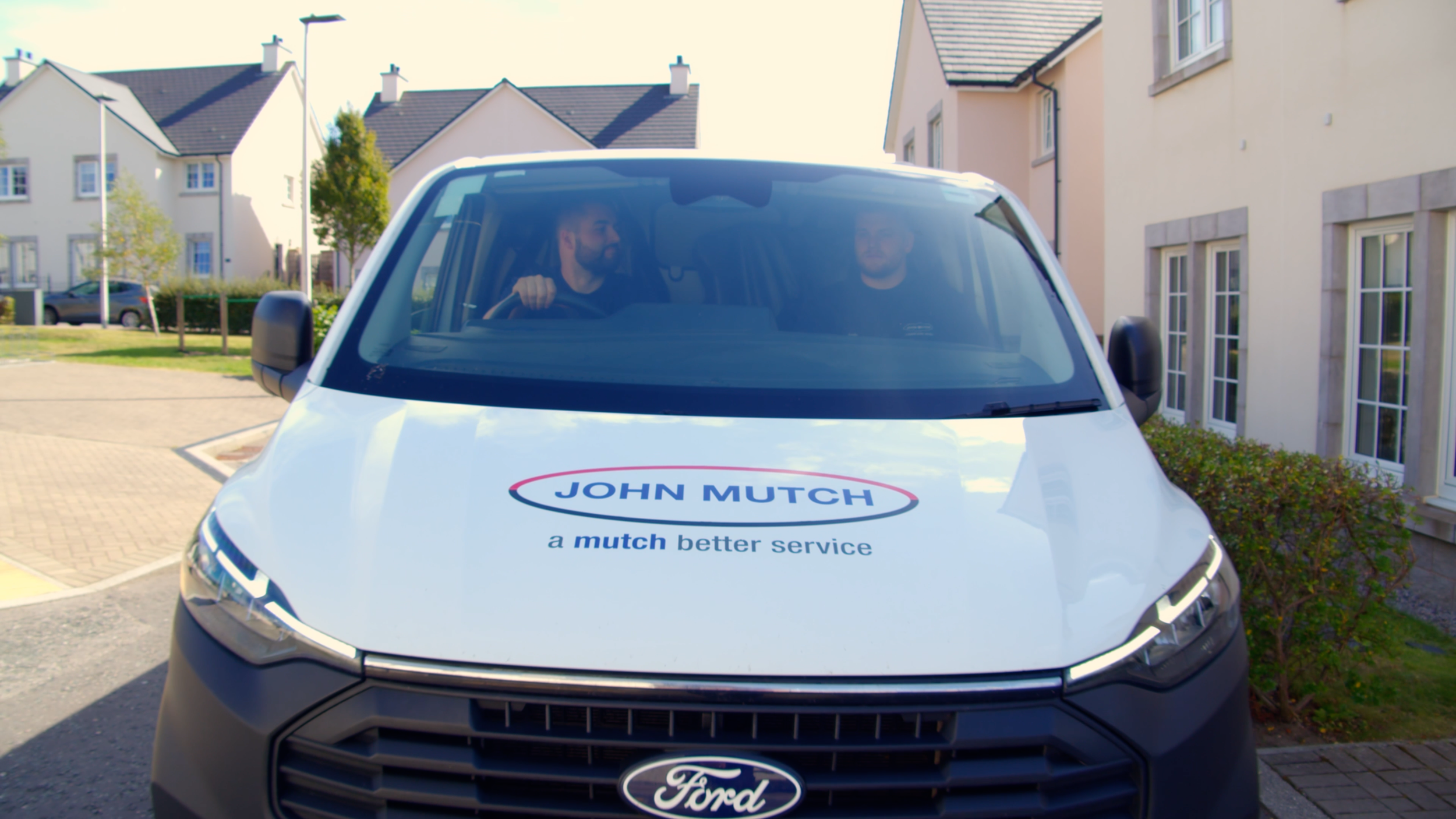 John Mutch Building Services van arriving at a home with two team members inside.