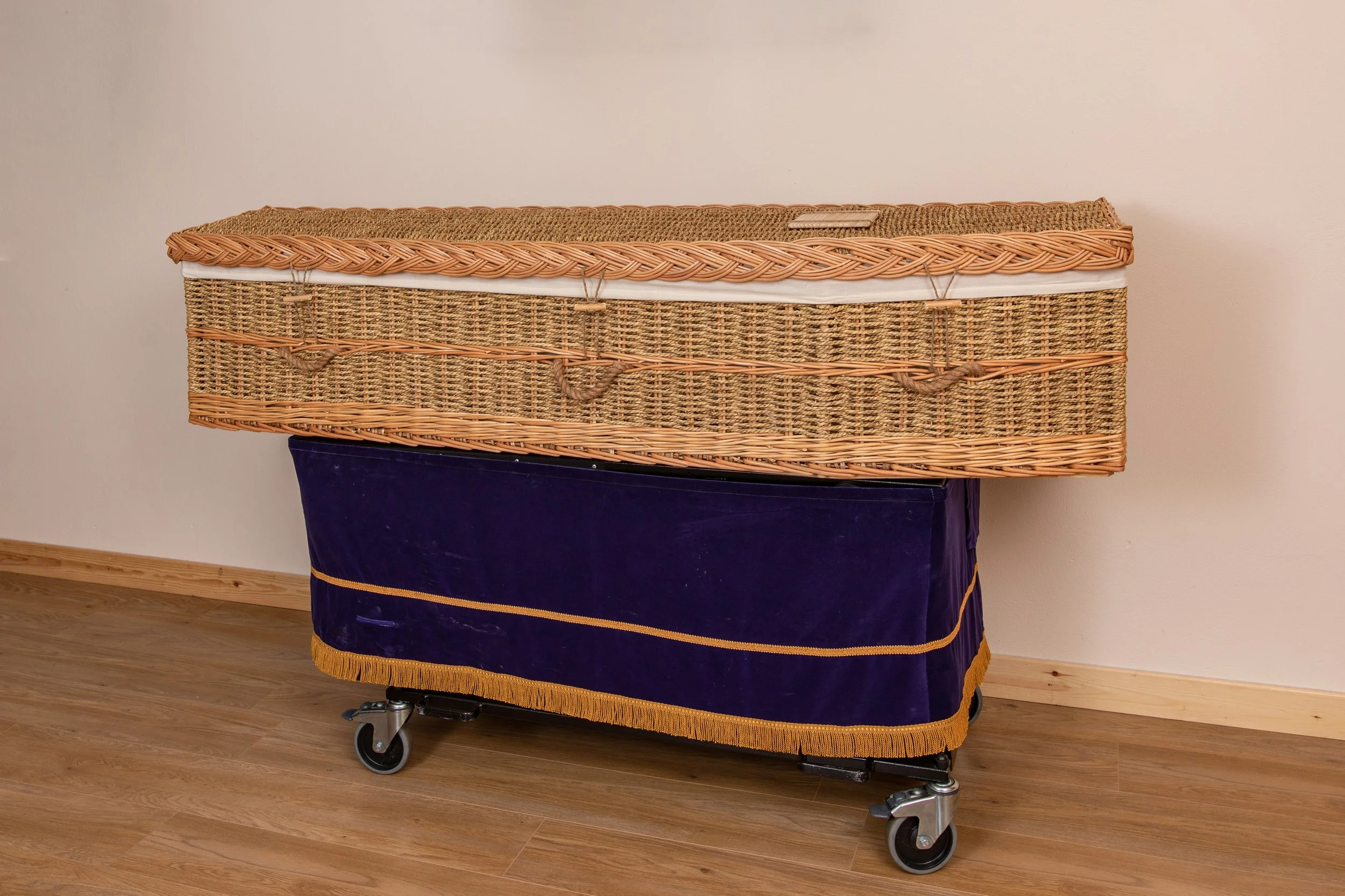 Wicker coffin seagrass with cotton interior. Wicker coffins are all natural so each one is individual. The one shown here is seagrass with cotton interior, engraved wooden name plate. 8 cords if required for burial.
