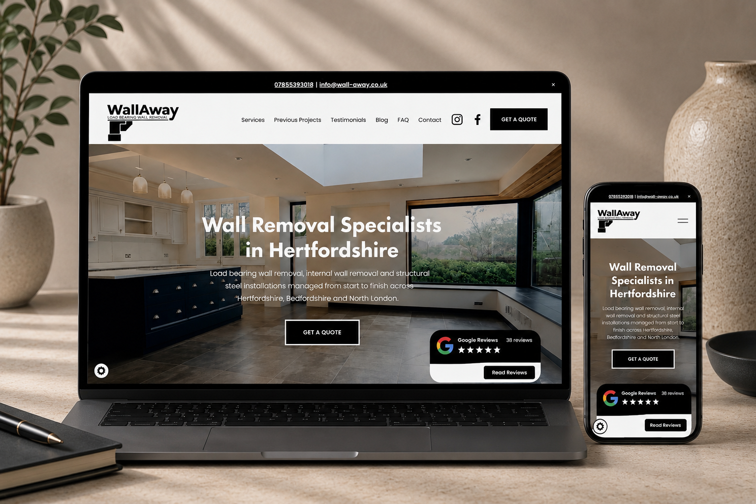 Laptop and smartphone displaying Wall Away website with text about wall removal specialists in Hertfordshire, set on a desk with decorative items around.