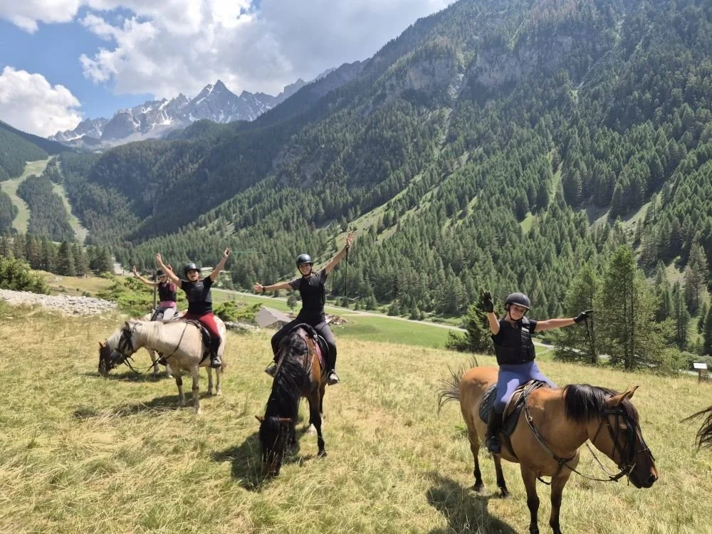 Trois personnes à cheval dans un paysage de montagnes verdoyantes avec ciel partiellement nuageux.