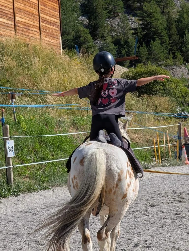 Jeune fille en casque à cheval sur un poney dans une zone d'équitation