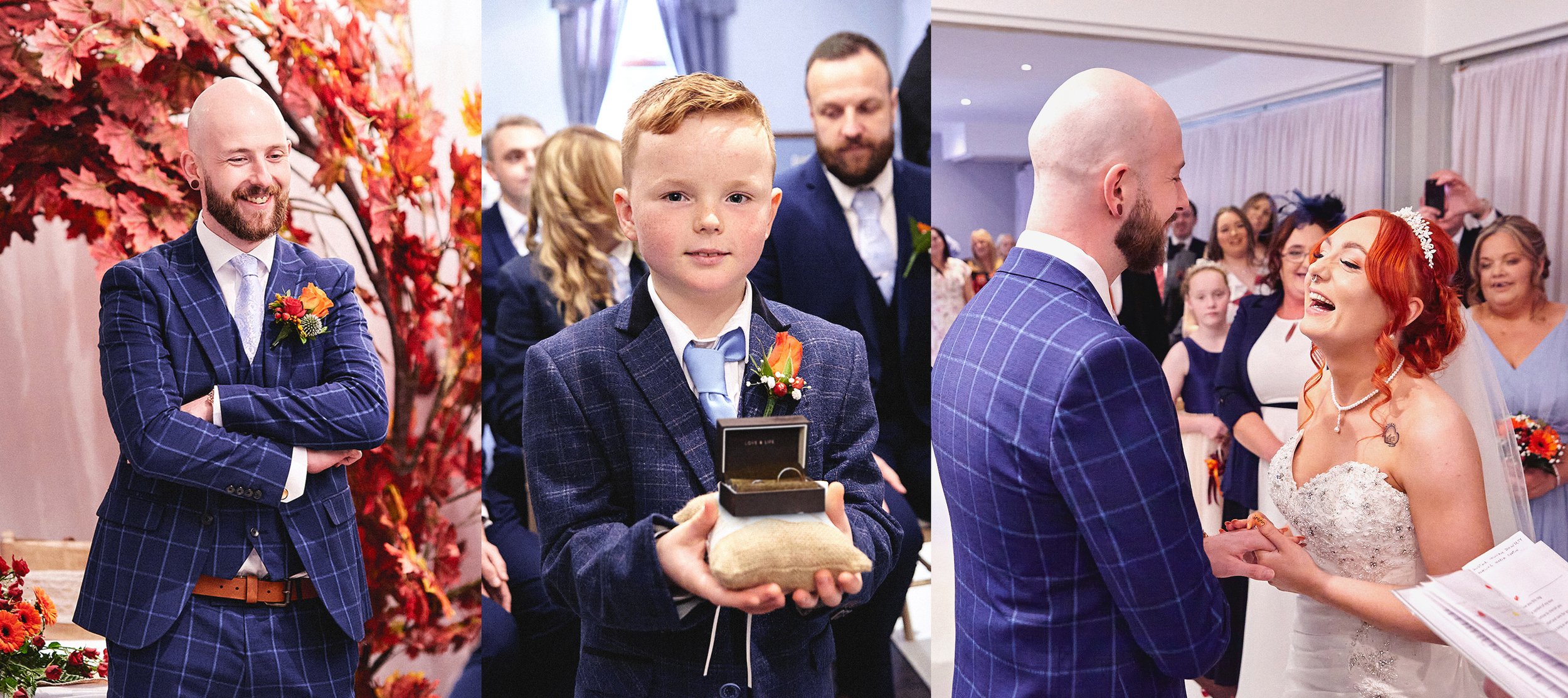 A man with a beard and a bald head is wearing a blue checkered suit with a white shirt and a tie, smiling with arms crossed. A young boy in a similar suit is holding a ring box with a gold ring inside and wearing a flower boutonniere on his jacket. A woman with red hair and a white wedding gown is holding hands with the man, smiling and looking at him during a wedding ceremony, with guests in the background.