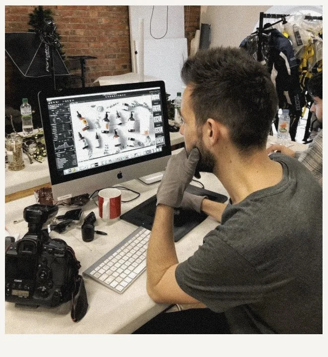 Young man analyzing a product photo on a computer screen in a creative workspace.