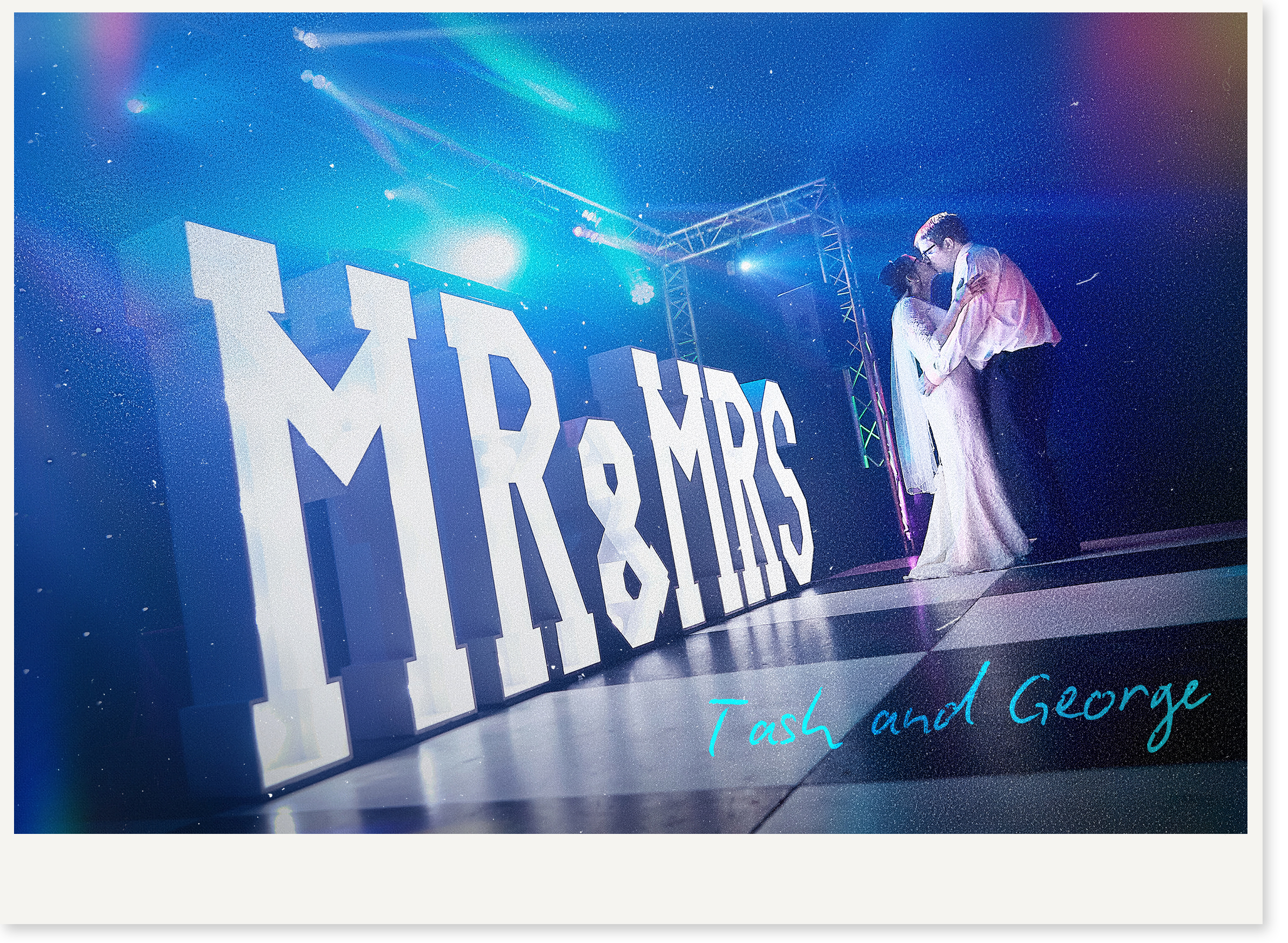 A brightly lit stage with large white 3D letters spelling 'MIDSUMMER' against a starry background and neon lights. Two people are embracing in the foreground, with one wearing glasses and a light-colored outfit, and the other in darker clothing. Text in teal reads 'Task and George' at the bottom.