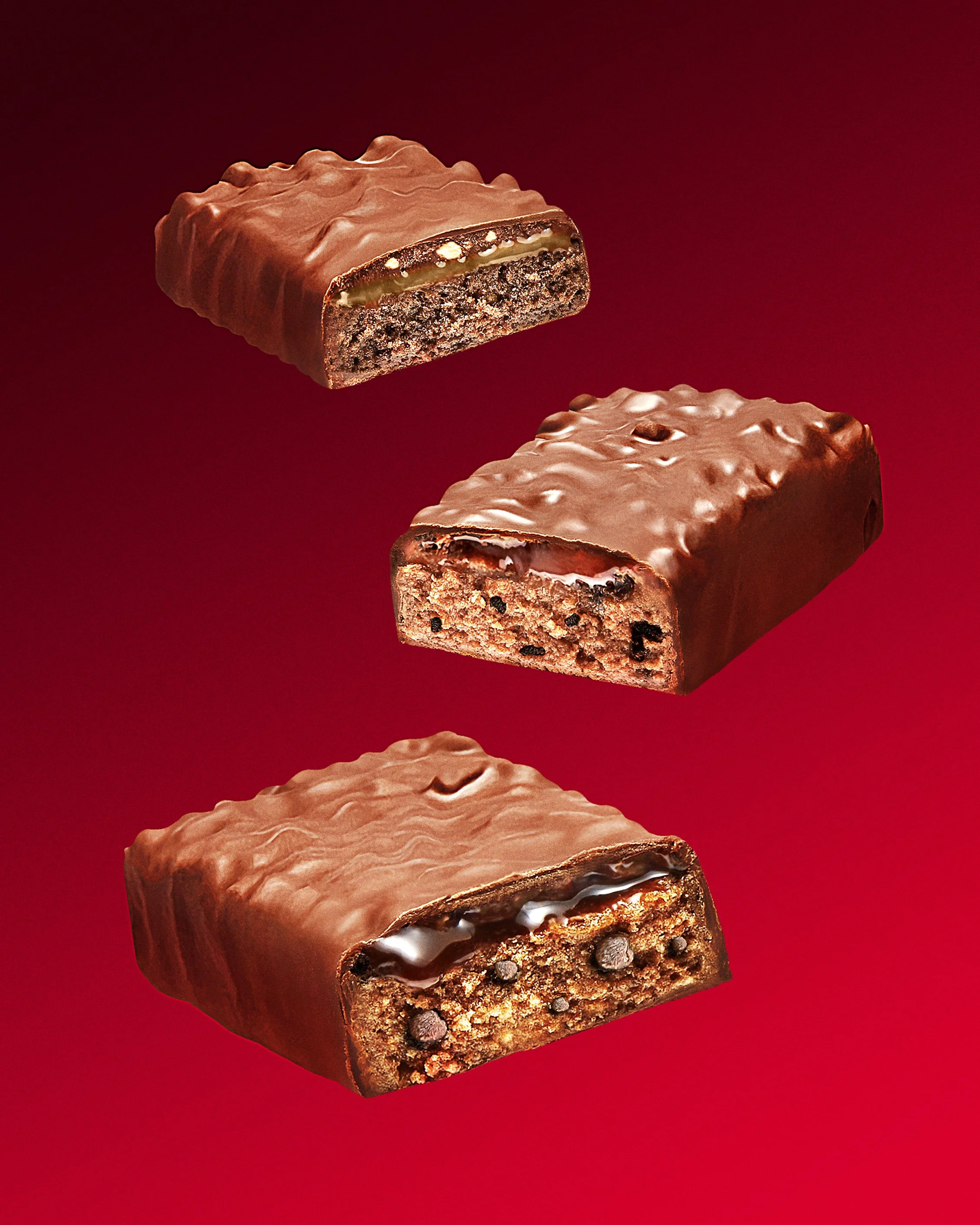 Three chocolate-covered cookies with different fillings, floating on a red background.