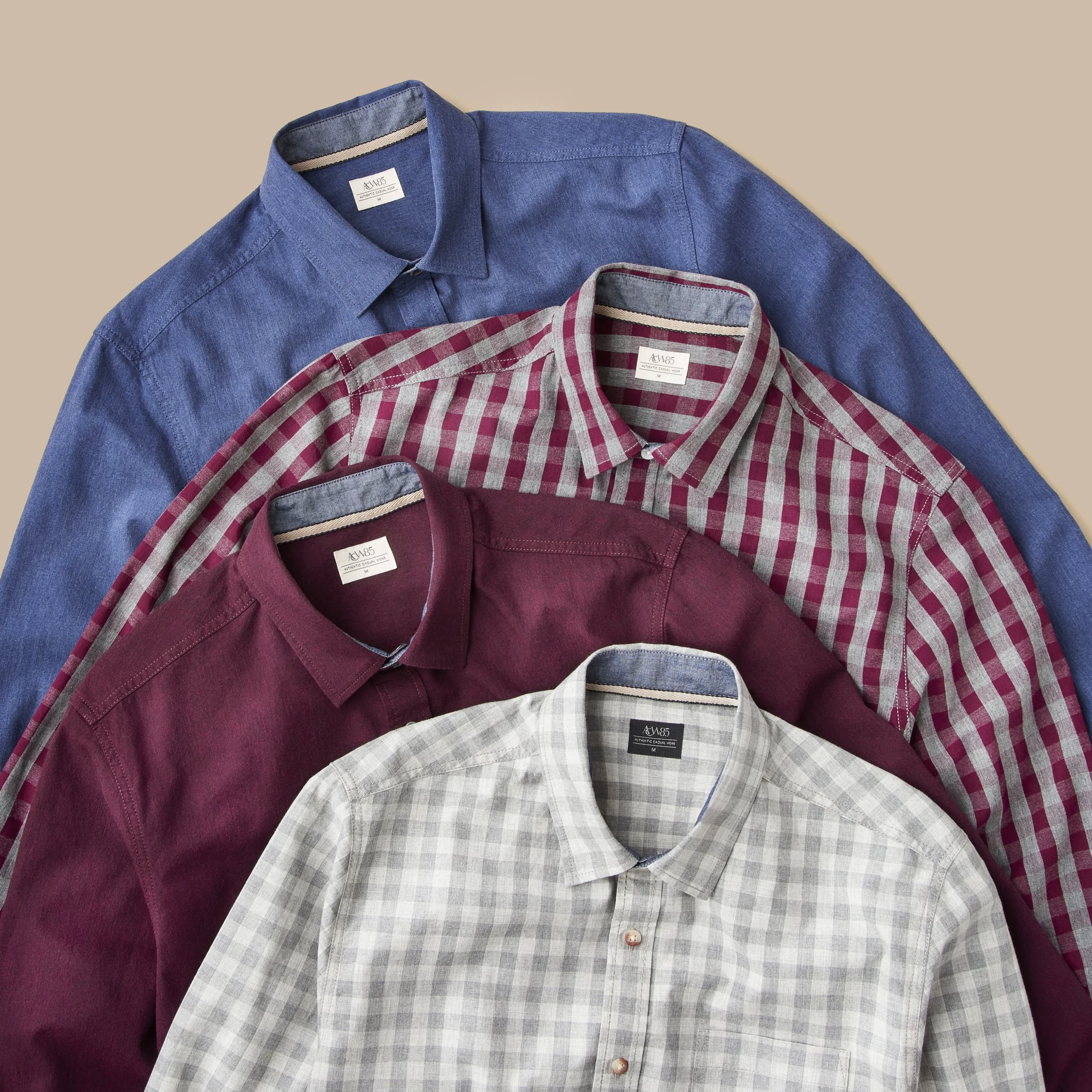 Three casual button-up shirts with plaid and solid colors, laid flat on a beige background, showing the collars and top buttons.
