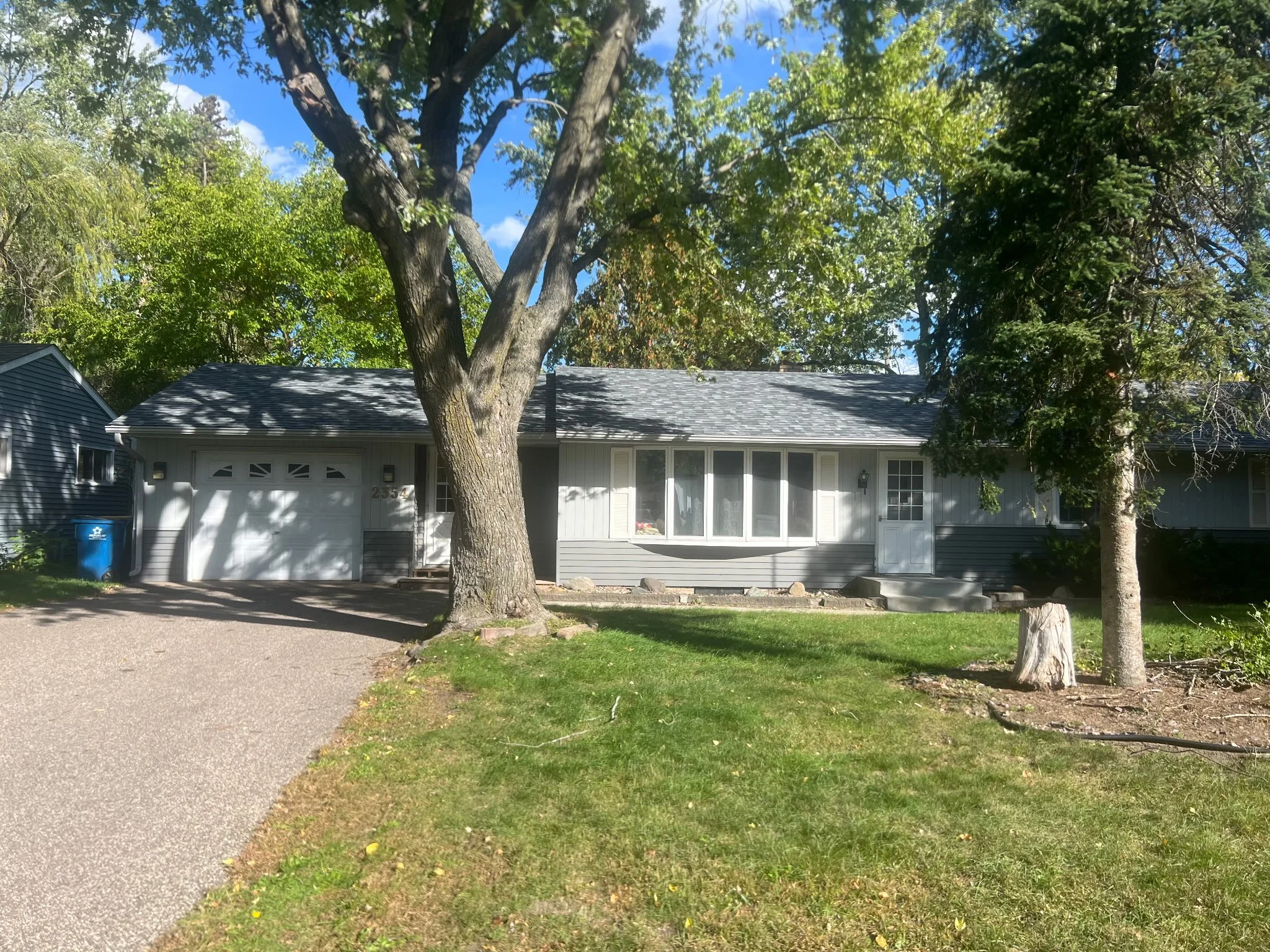 Circle Drive home: single-story gray house with an attached garage, a large shade tree, and a front lawn