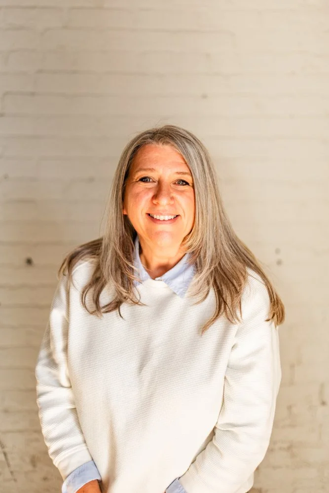 Headshot of Caryn Conway standing in front of a white brick wall