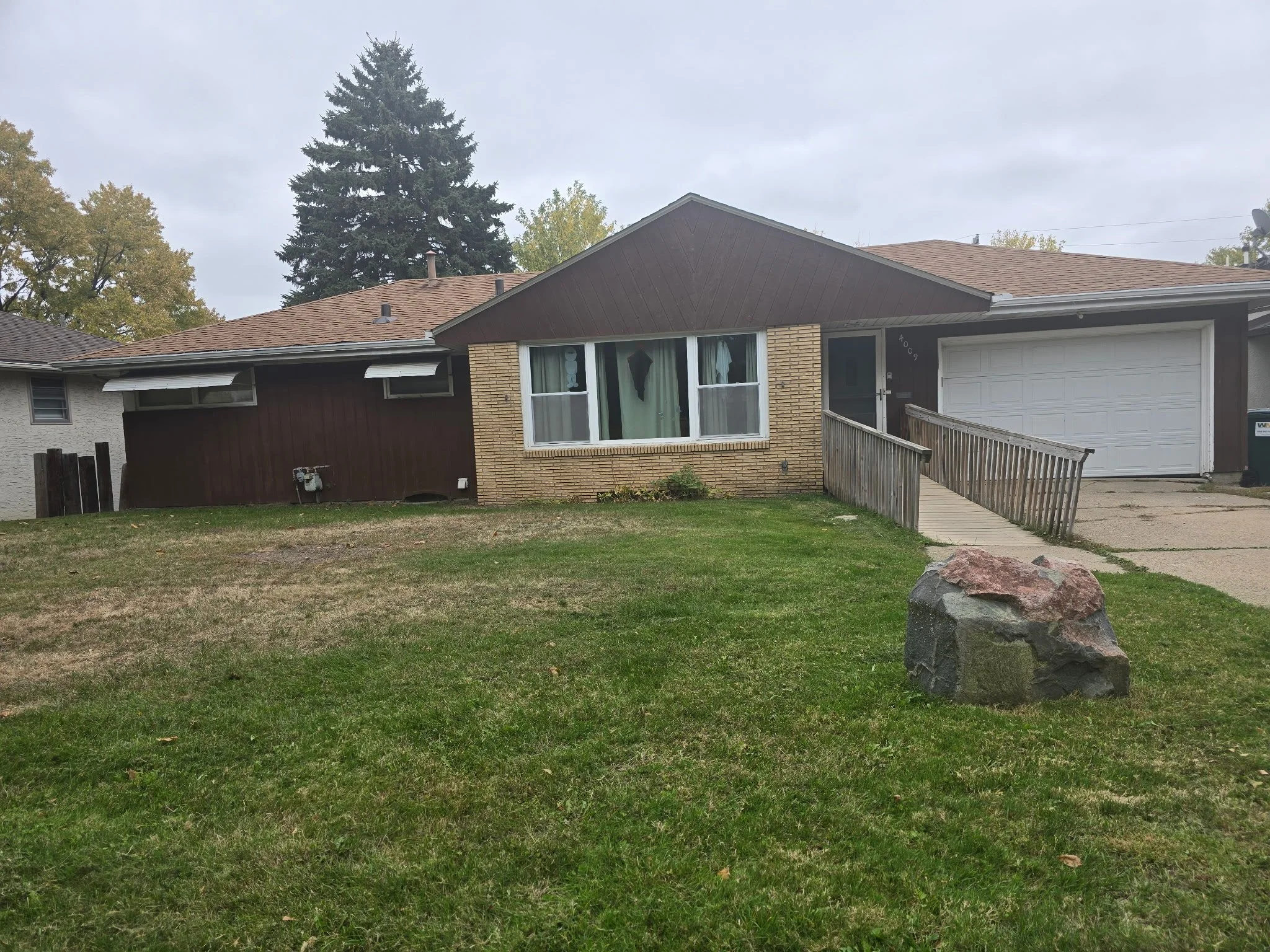 Arthur home: single-story house with a tan brick and brown exterior, a front lawn, and a wheelchair ramp to the entrance