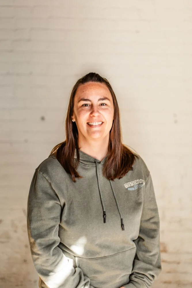 Headshot of Nicole Maxwell standing in front of a white brick wall