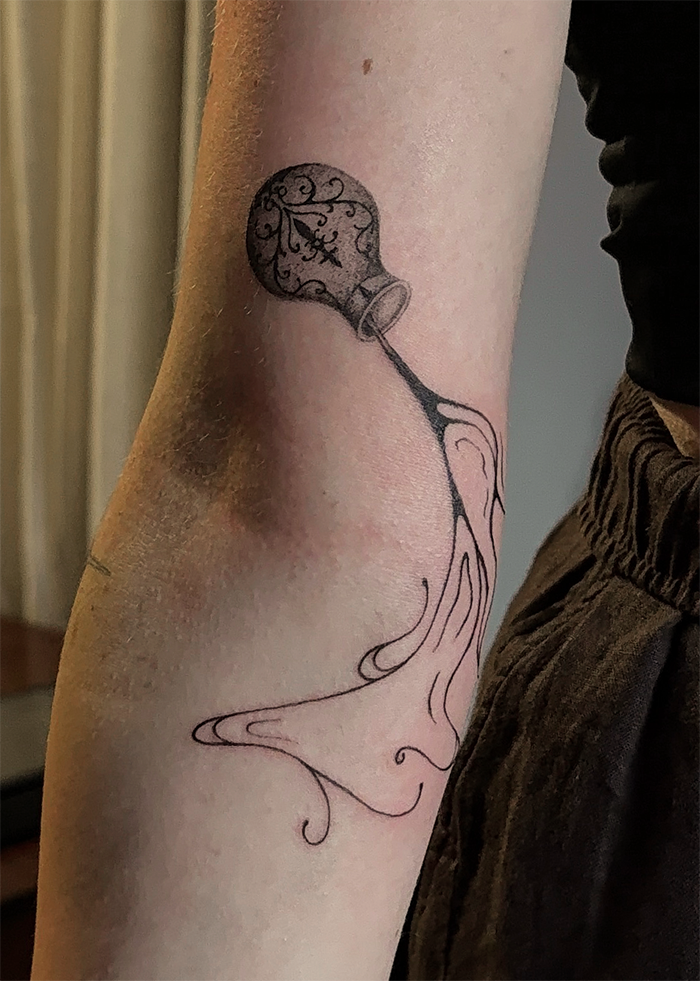 Tattoo van een gloeilamp met een binnenwerk van krullende lijnen en elektrische inrichtingen.