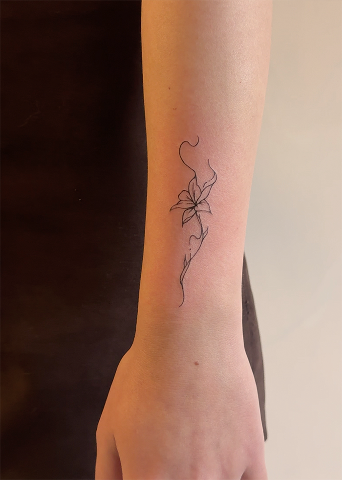 Tattoo van een bloem op de onderarm