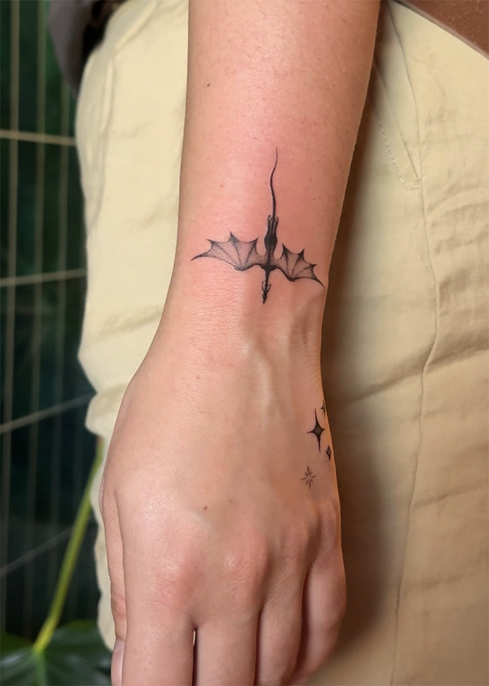 Tattoo van een vleermuis op de pols van een persoon.