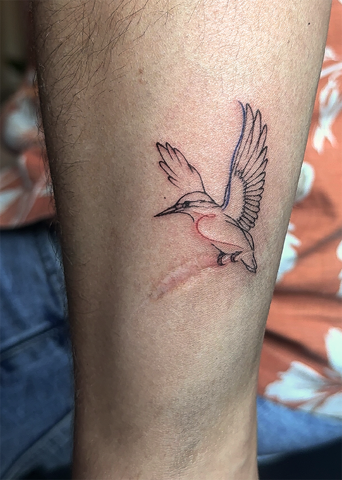 Een tatoeage van een vogel in vlucht op de onderarm.