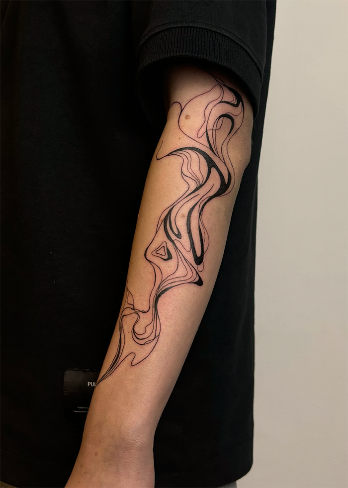 Tattoo van abstracte, golvende lijnen in zwart op onderarm