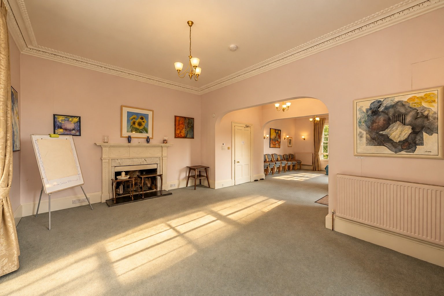 Garden Room at Cullerne House in Findhorn, with open floor space, a fireplace and connecting arches.
