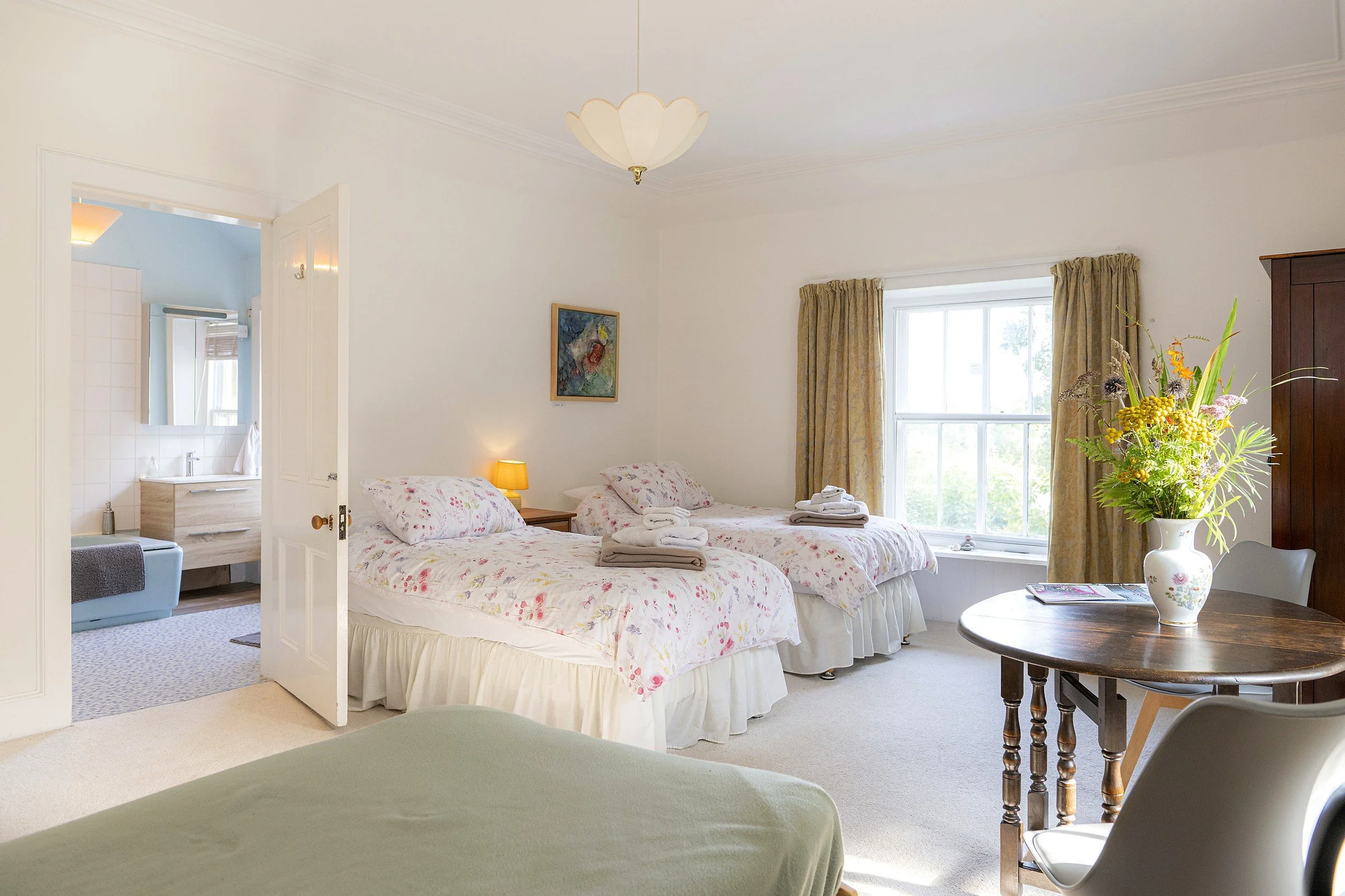Ruby twin room at Cullerne House B&B in Findhorn with floral bedding, ensuite entrance and garden-facing window.