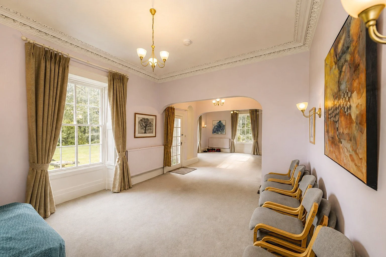 Workshop rooms at Cullerne House in Findhorn with connecting arches, tall windows, artwork and chairs.