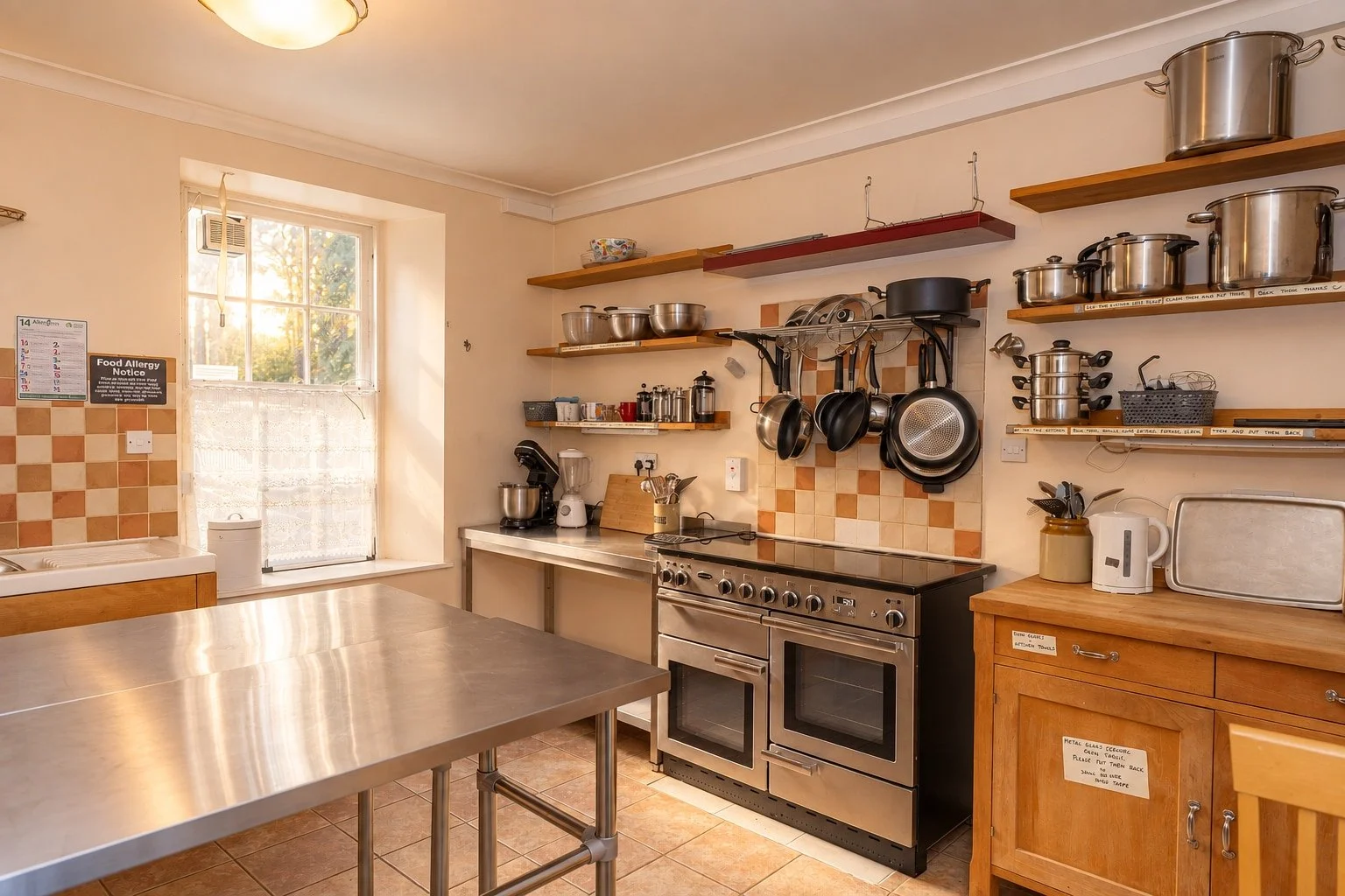 Kitchen at Cullerne House in Findhorn, with a range cooker, stainless-steel preparation table and cookware.