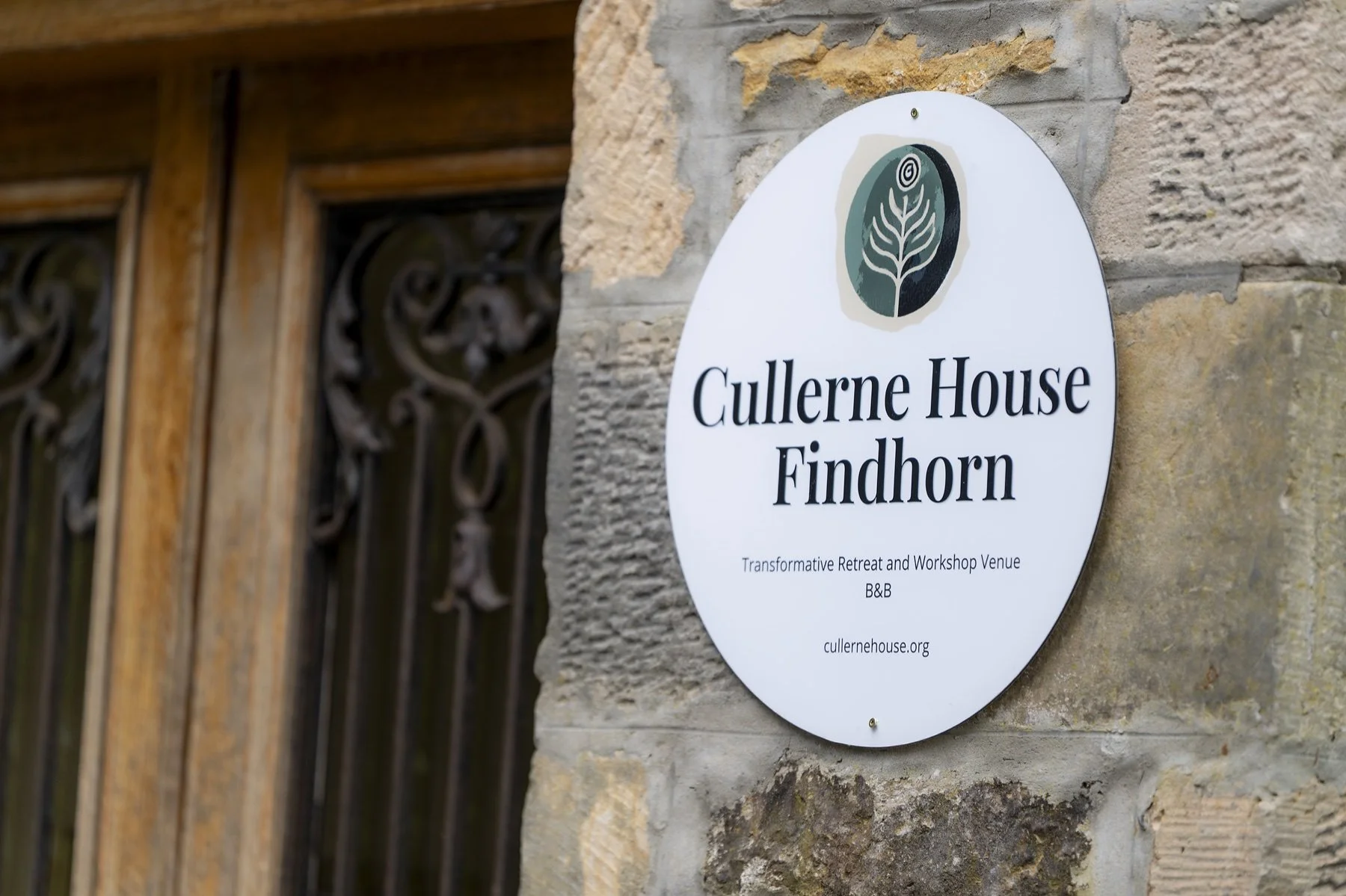 Cullerne House Findhorn sign on the stone wall beside the wooden entrance.
