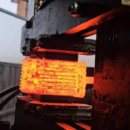 A glowing red hot metal piece in a blacksmithing forge being shaped.