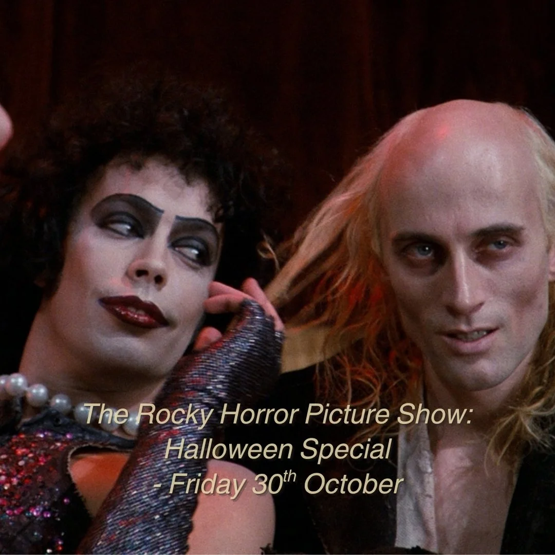 A scene from The Rocky Horror Picture Show with two characters dressed in elaborate costumes, one with dark makeup and curly hair, and the other with long blond hair. Text overlay reads: 'The Rocky Horror Picture Show: Halloween Special - Friday 30th