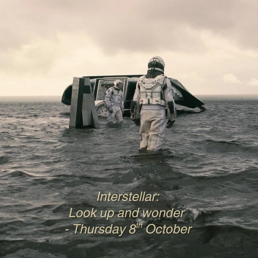 Two astronauts in space suits standing in the water near a spacecraft on an ocean surface under a cloudy sky, with text that reads "Interstellar: Look up and wonder - Thursday 8th October."
