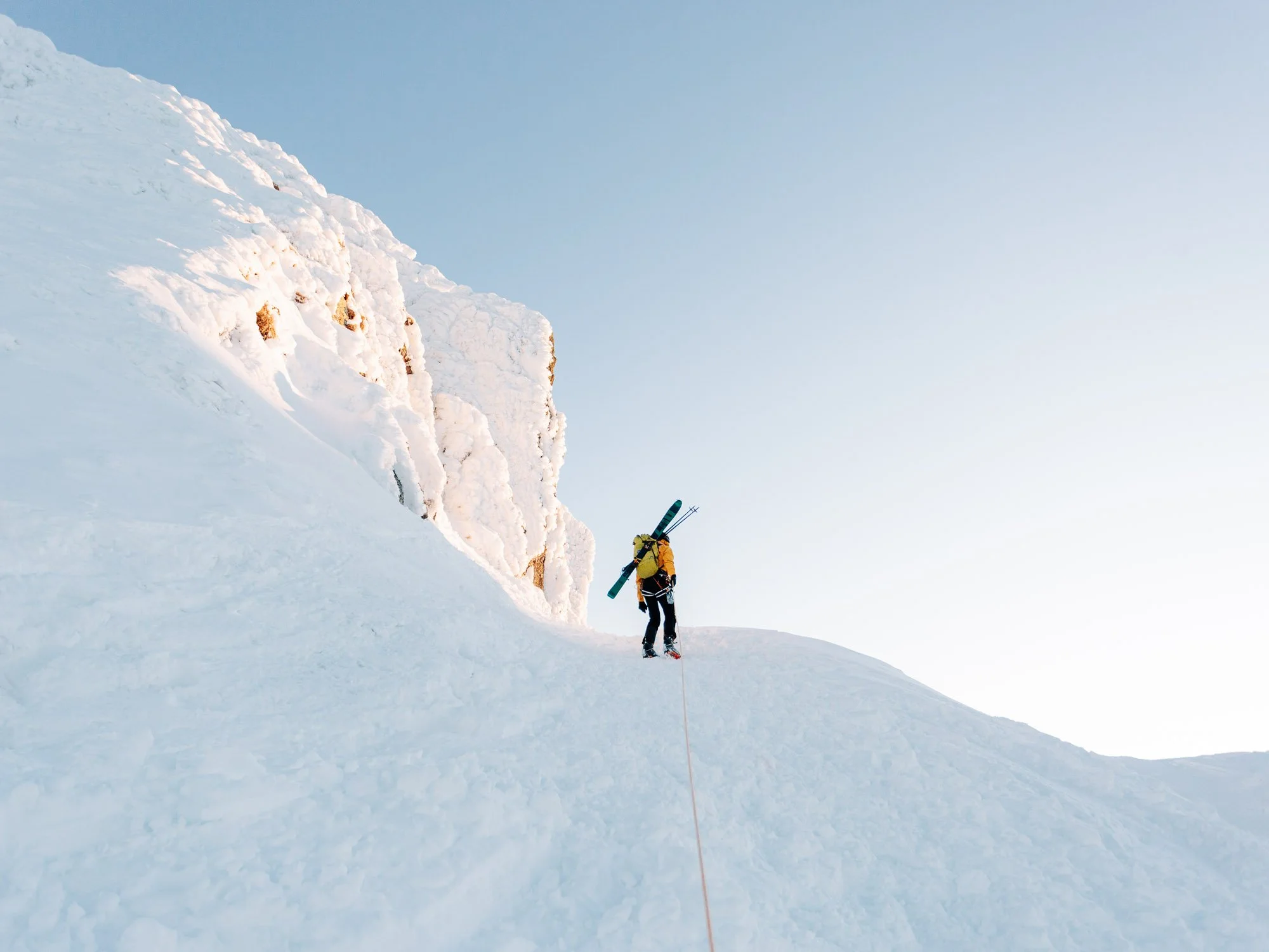 Deux skieurs en montagne recouverte de neige, avec un ciel dégagé.