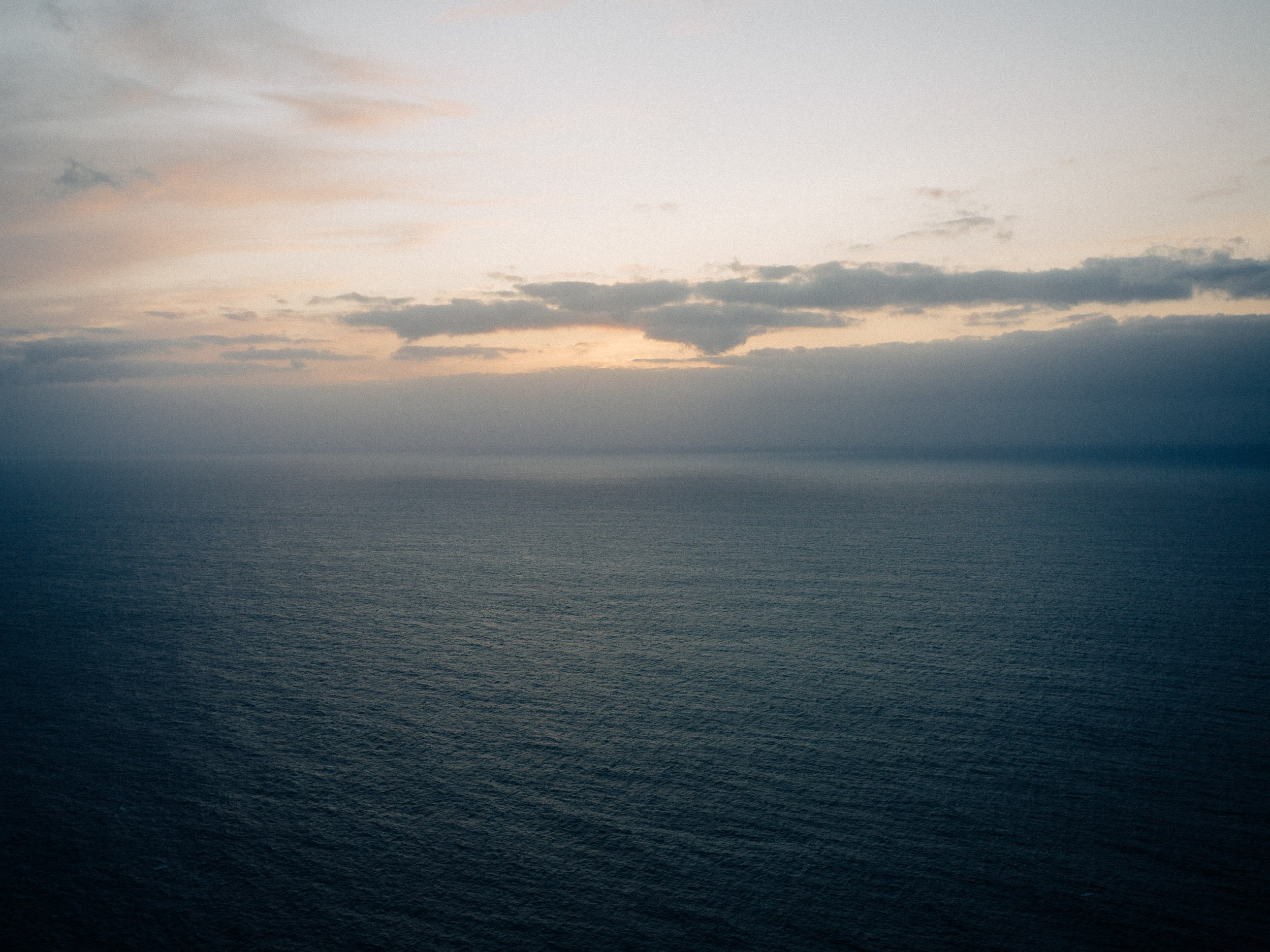 Ciel nuageux au-dessus de la mer ou de l'océan, avec une lumière douce et une ambiance calme.
