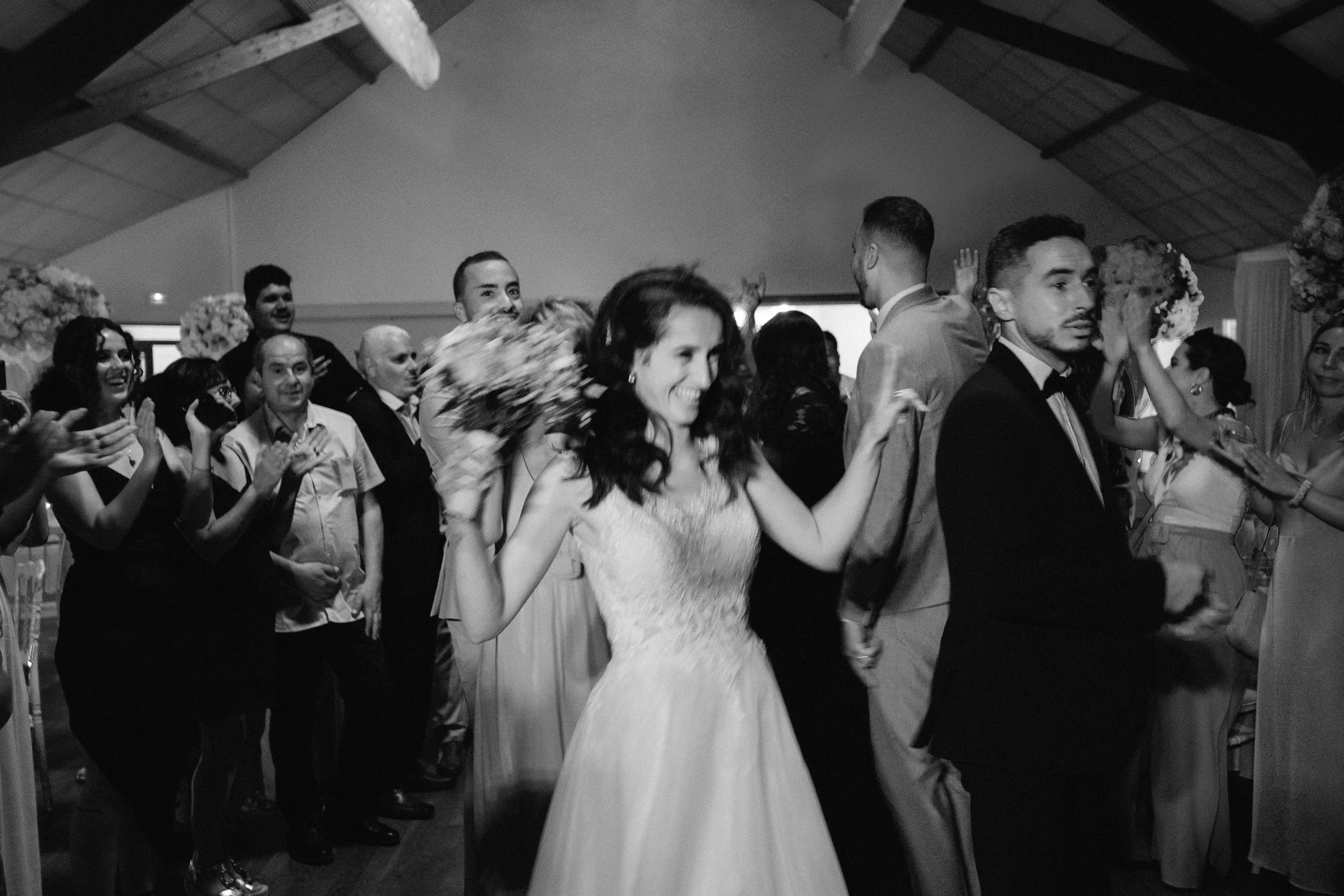 Un groupe de personnes dansant lors d'une réception ou d'un mariage, dans une pièce avec un plafond en bois.