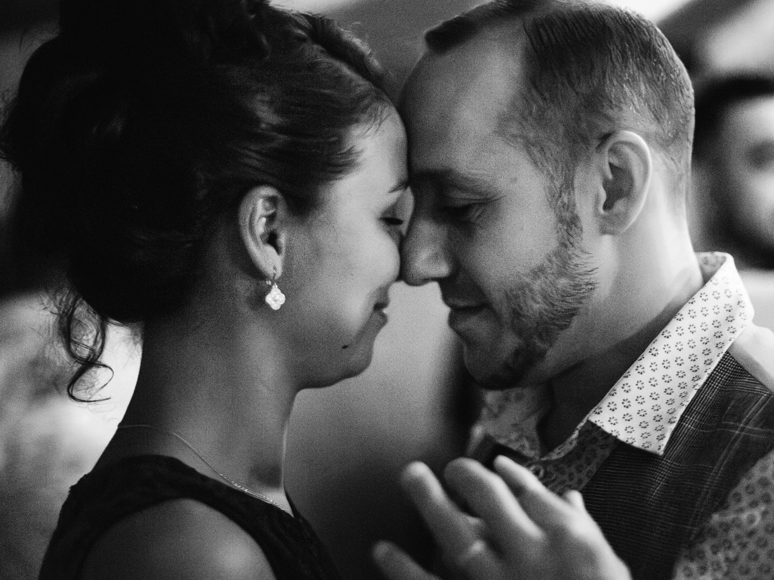 Un couple se tenant tête contre tête, partageant un baiser intime en noir et blanc.