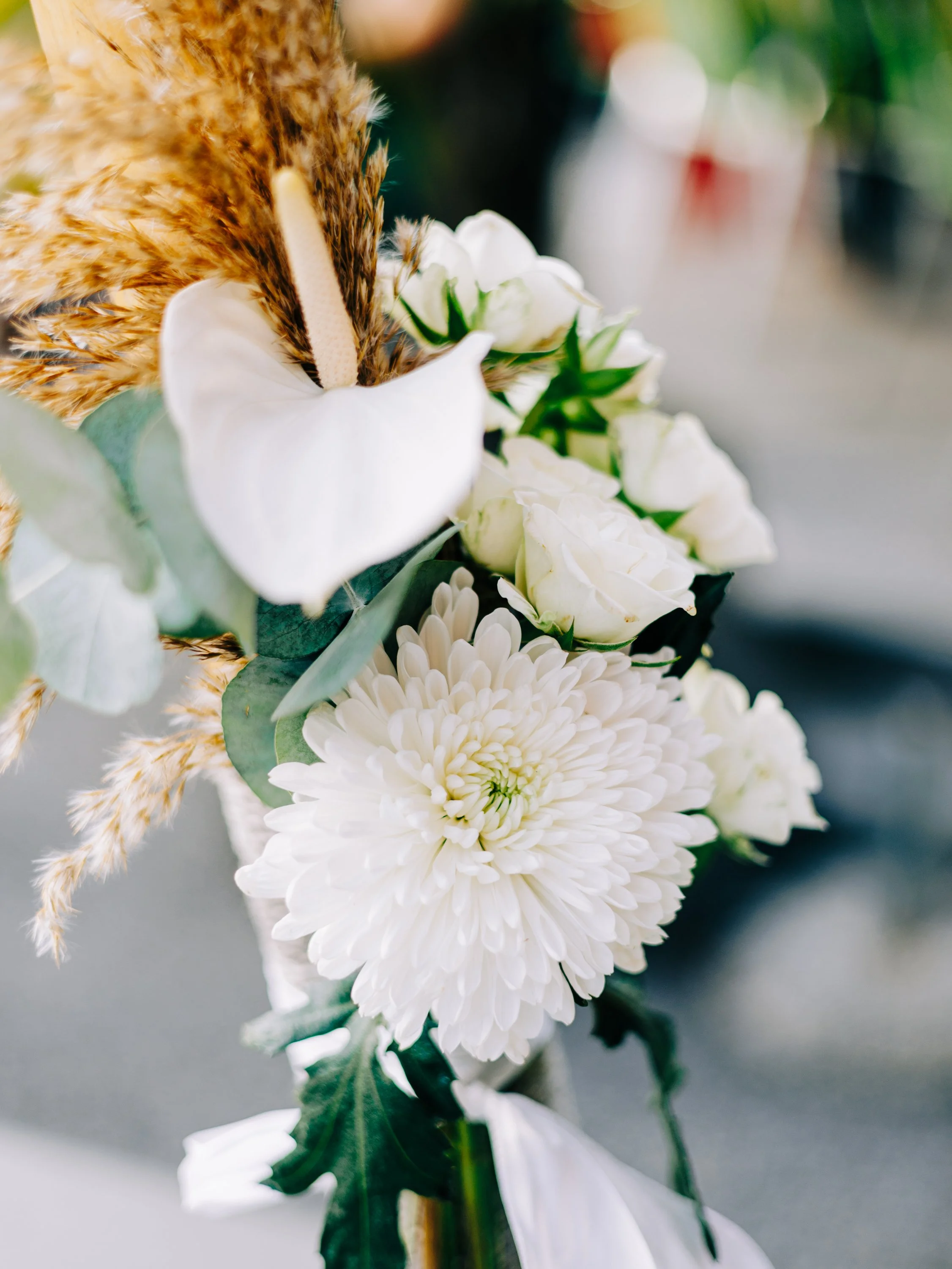 Bouquet de fleurs blanches avec une fleur d'anthurium, un chrysantheme et de la pampa, décoration nue avec ruban blanc.