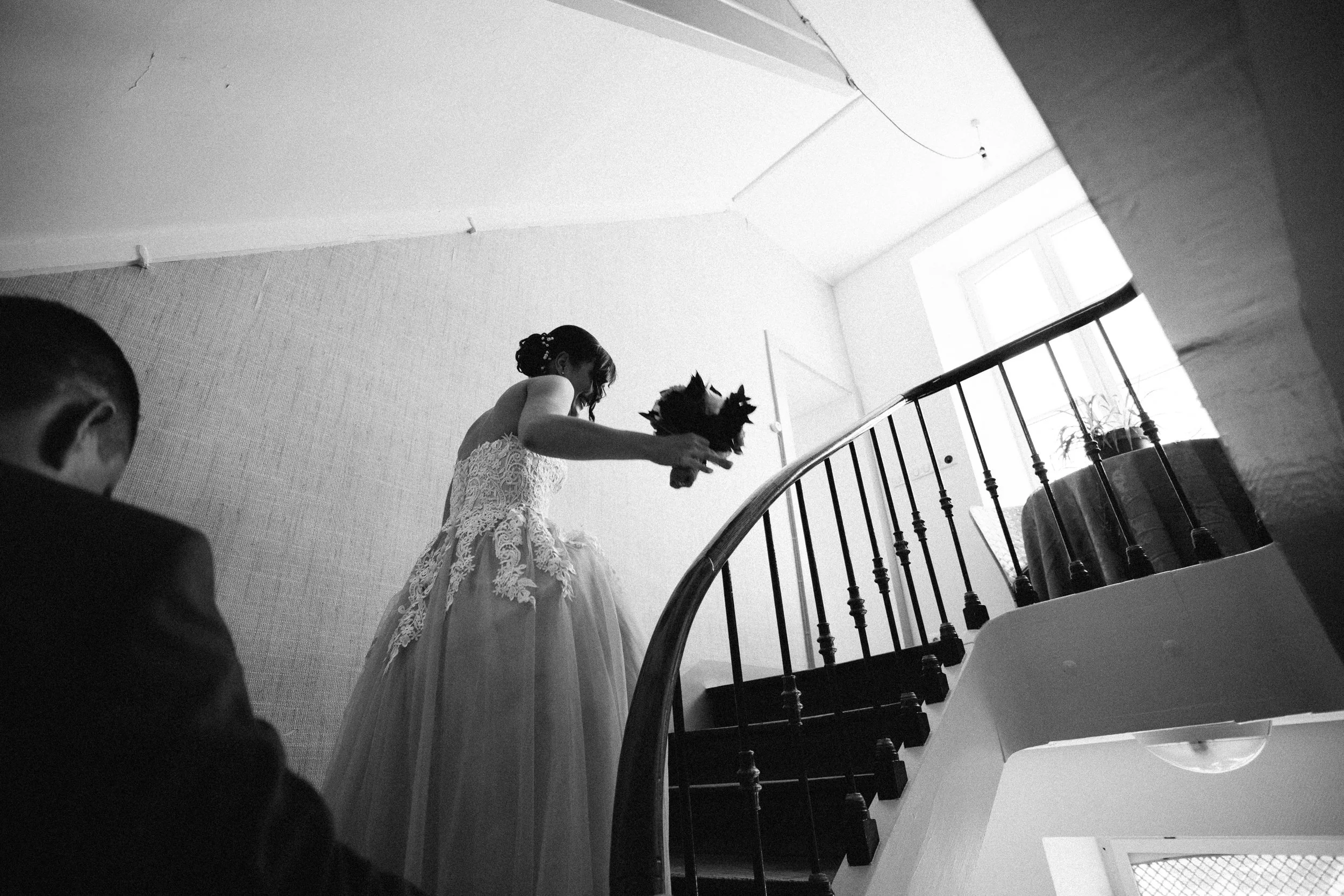 Une femme en robe de mariée tenant un bouquet de fleurs, vue en contre-plongée dans un intérieur lumineux.