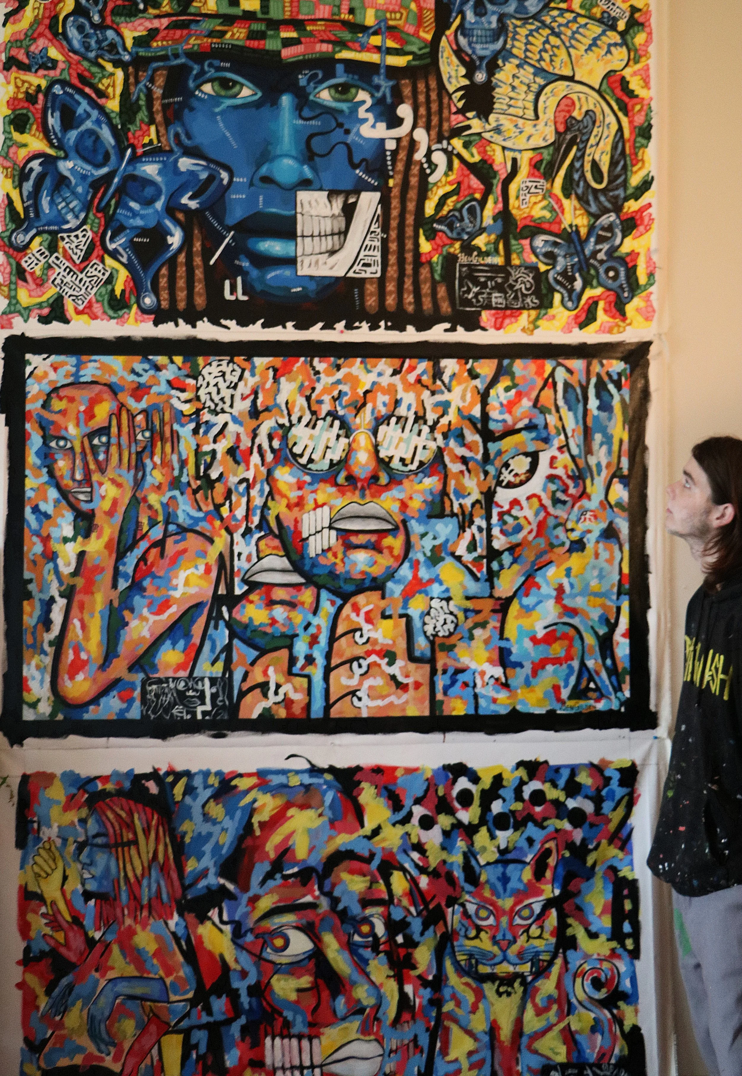 Colorful street art murals featuring abstract and fantastical portraits, with vibrant reds, blues, yellows, and greens, including stylized human faces, animal motifs, and graffiti elements.