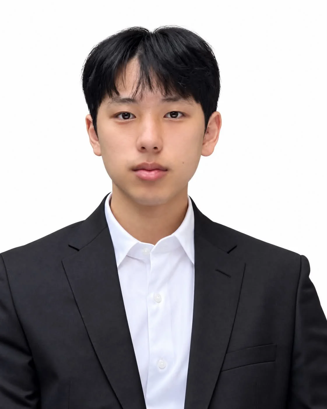A young man with black hair wearing a white shirt and black suit against a plain white background.