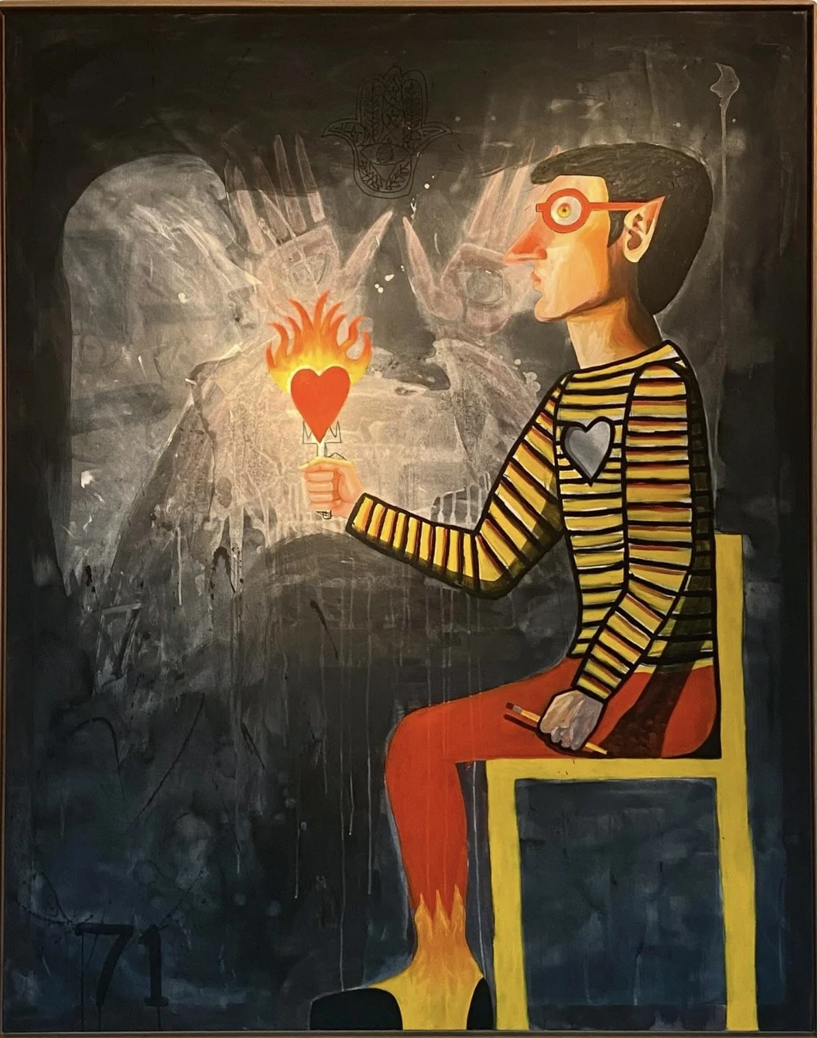 Un garçon assis sur une chaise en bois, portant un pull rayé jaune et noir avec un cœur gris, regarde vers la droite et tient une bougie en forme de cœur enflammée. En arrière-plan, un tableau d'école noir est décoré d'une peinture colorée.