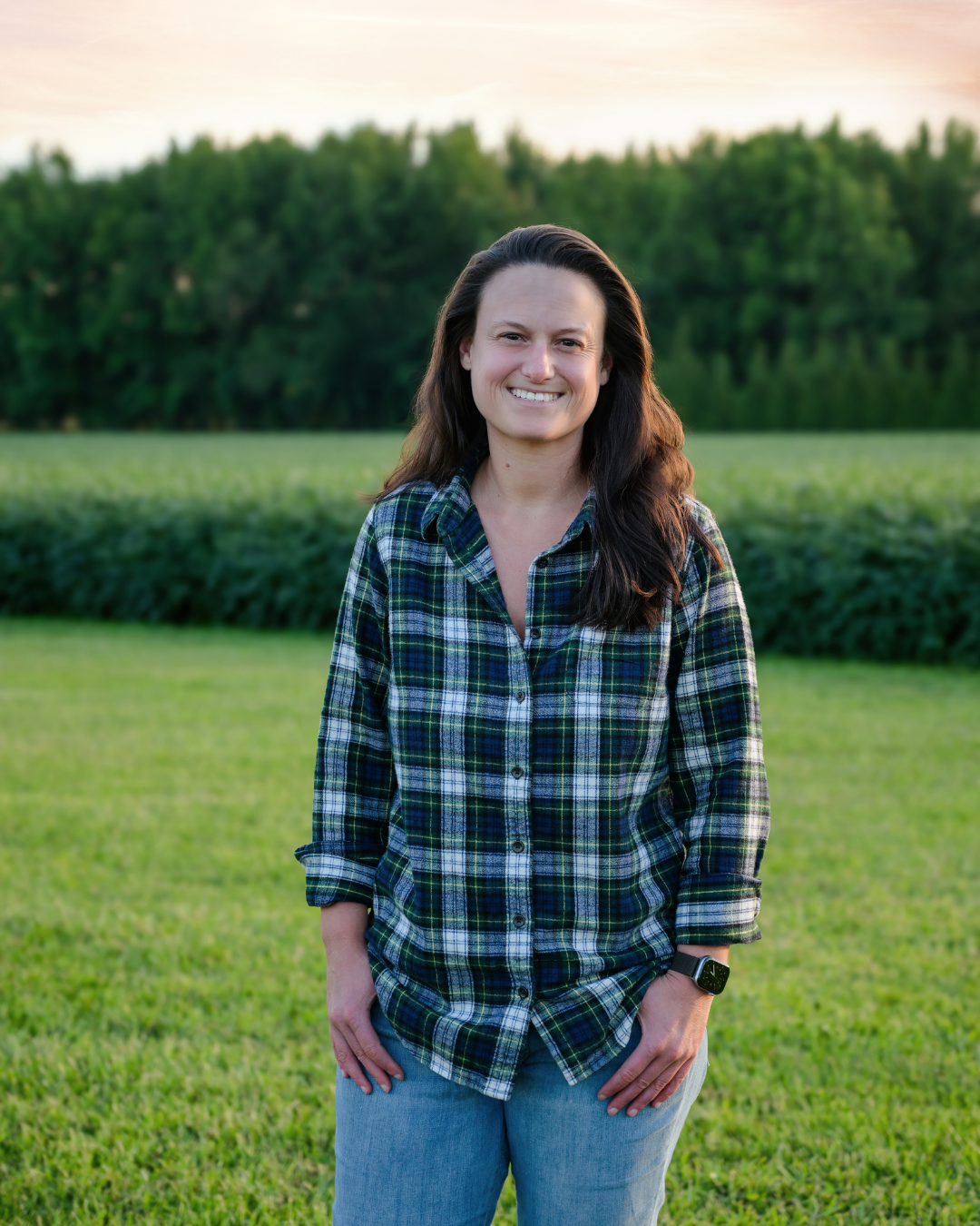 Tori Parker standing near a corn field. Long dark brown hair, flannel shirt.