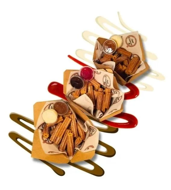 Three small Que Churro Boxes filled with churros and topped with different sauces and chocolates, arranged on a white surface with colorful sauce drizzles underneath.