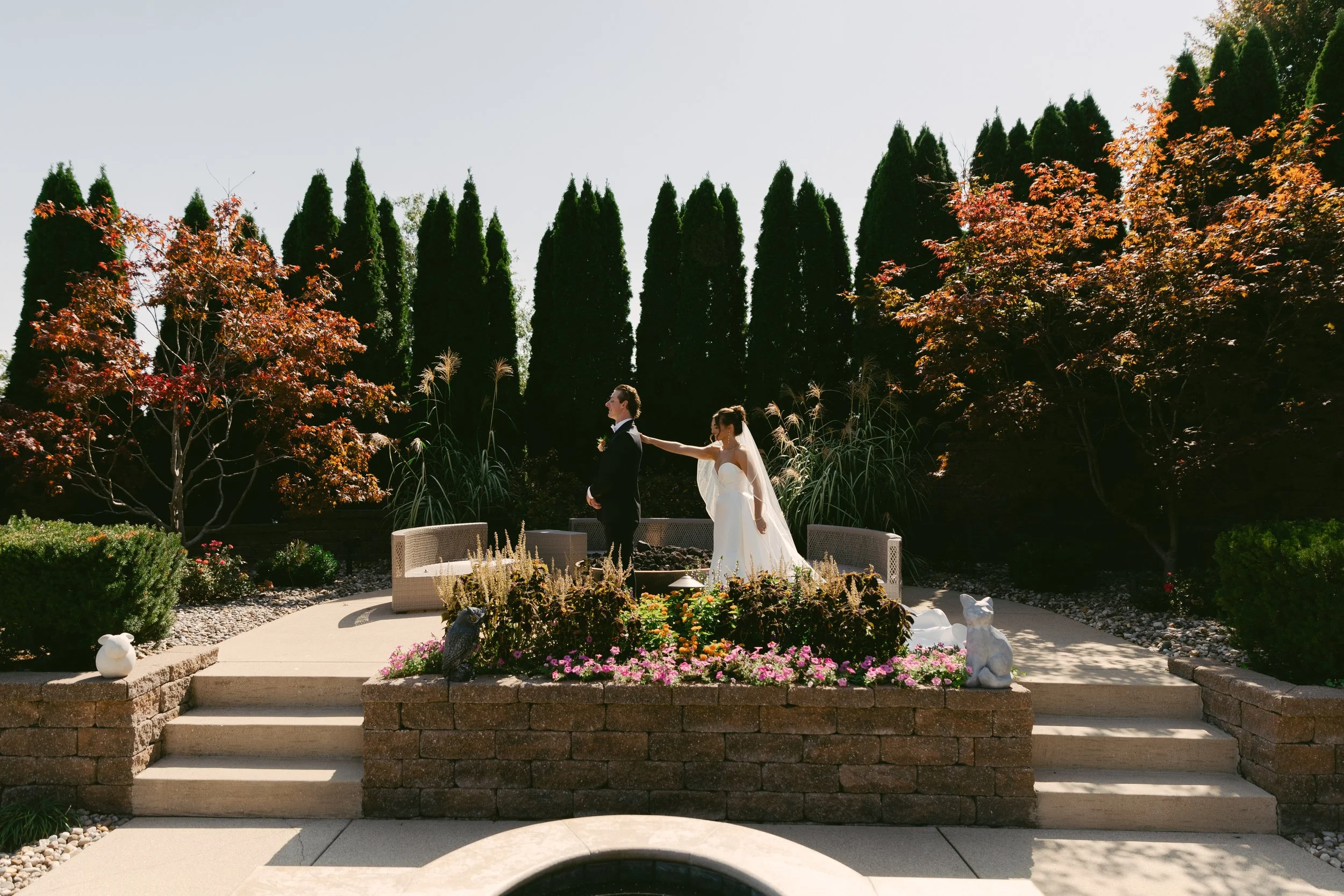 St. Louis Documentary-style wedding photography on 35mm film, 120 film, and digital by Trevor Lovatto. A bride and groom stand on an outdoor wedding altar surrounded by a garden with autumn foliage, tall trees, and vibrant flowers.